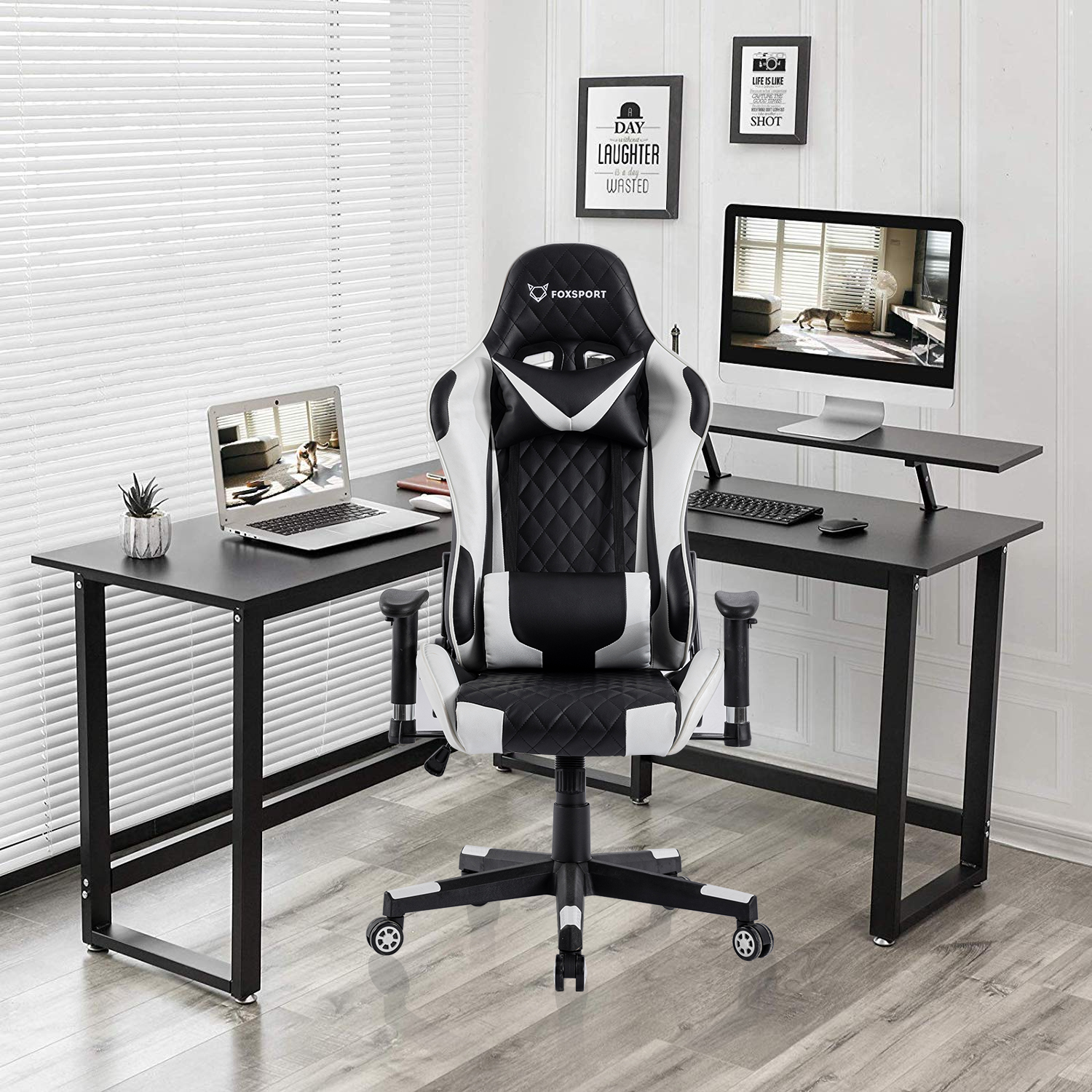 Schwarzer Schreibtisch mit weiß-schwarzem Gaming-Stuhl, Laptop und Monitor. Hintergrund: Fenster und Dekorationen.