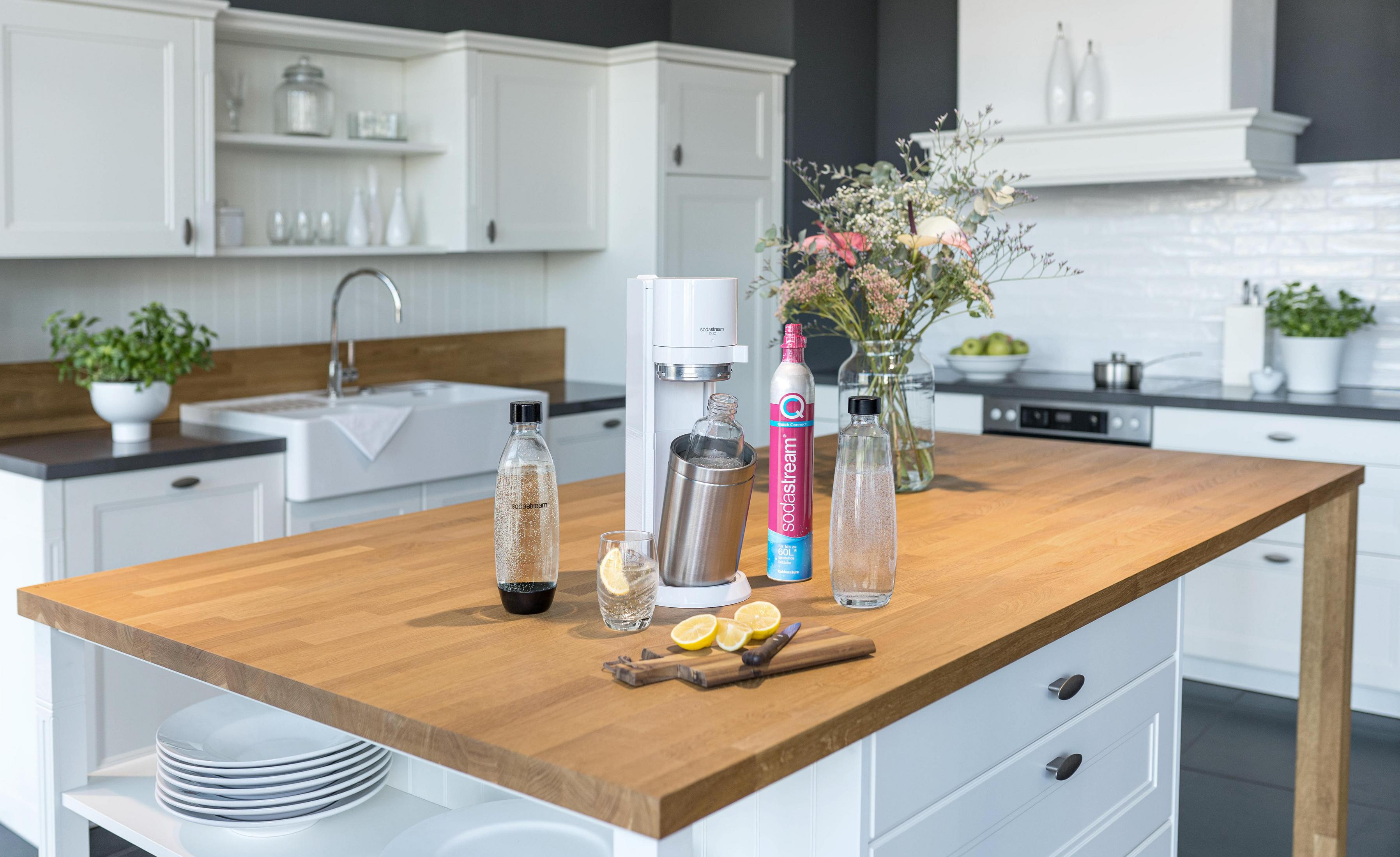 Wyspa kuchenna z saturatorem, butelkami i cytrynami. W tle kuchnia.