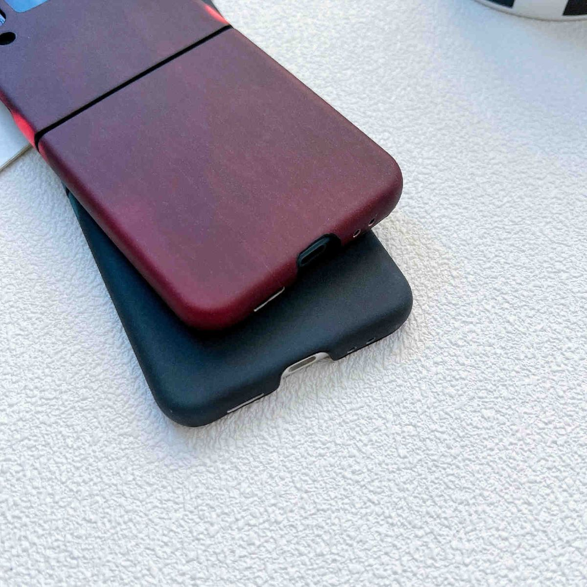 Zwei Telefonhüllen gestapelt. Die obere ist weinrot, die untere schwarz.