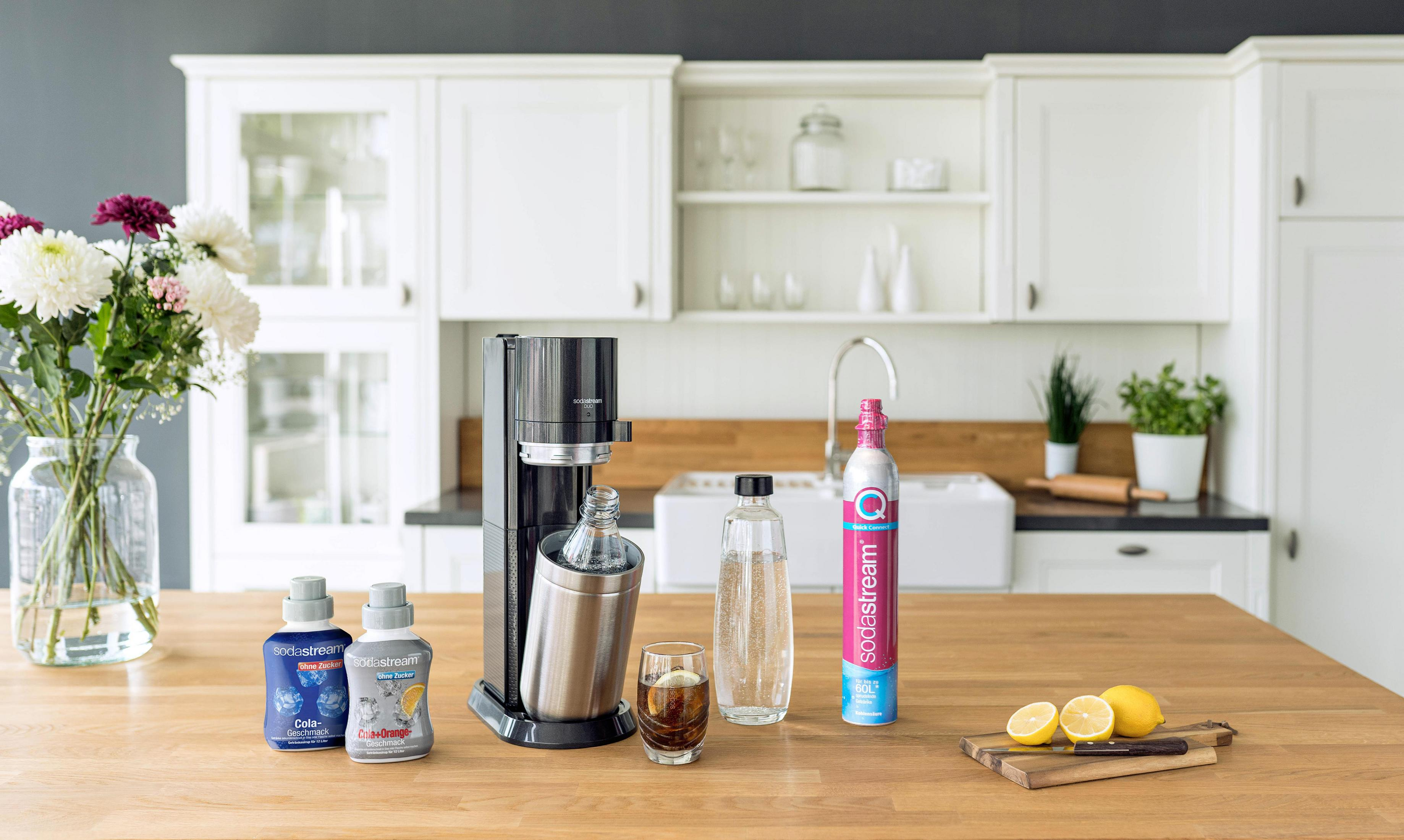 Maszyna SodaStream na blacie z składnikami i szklanką.