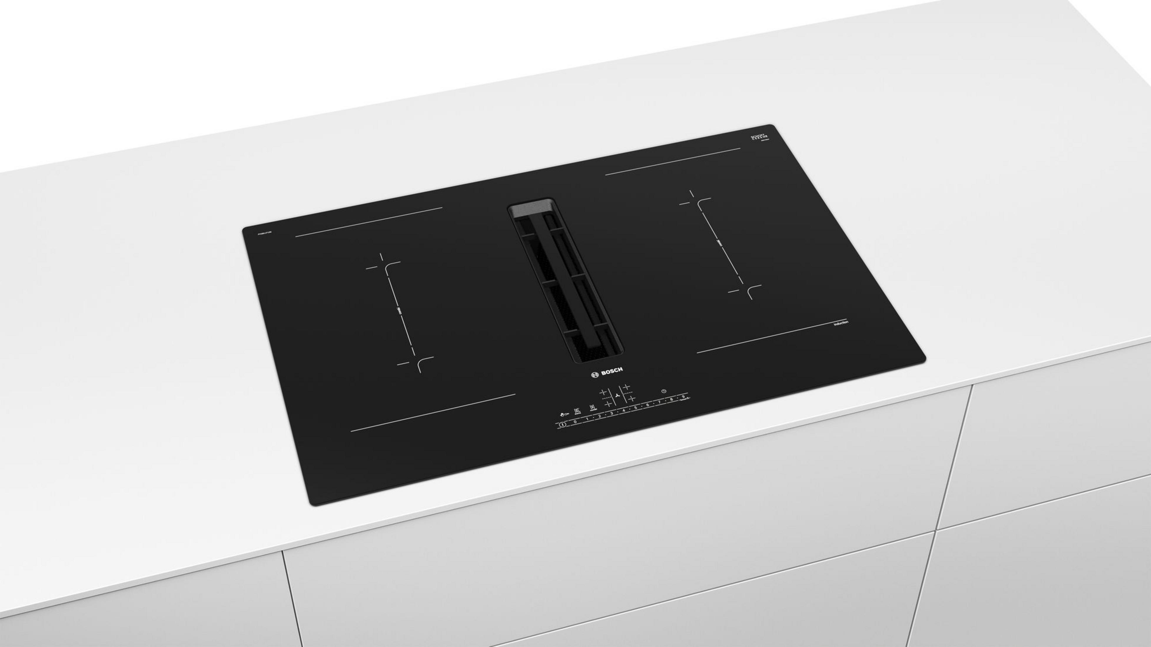 Piano cottura nero integrato su un piano di lavoro bianco. Ha un estrattore integrato e comandi touch.