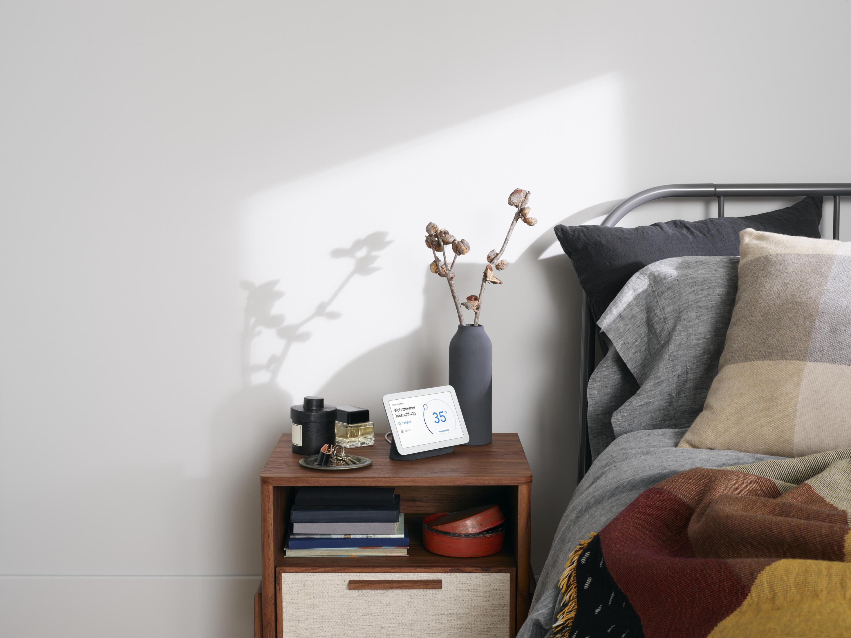 Un comodino con un display intelligente che mostra 35 gradi e un vaso.