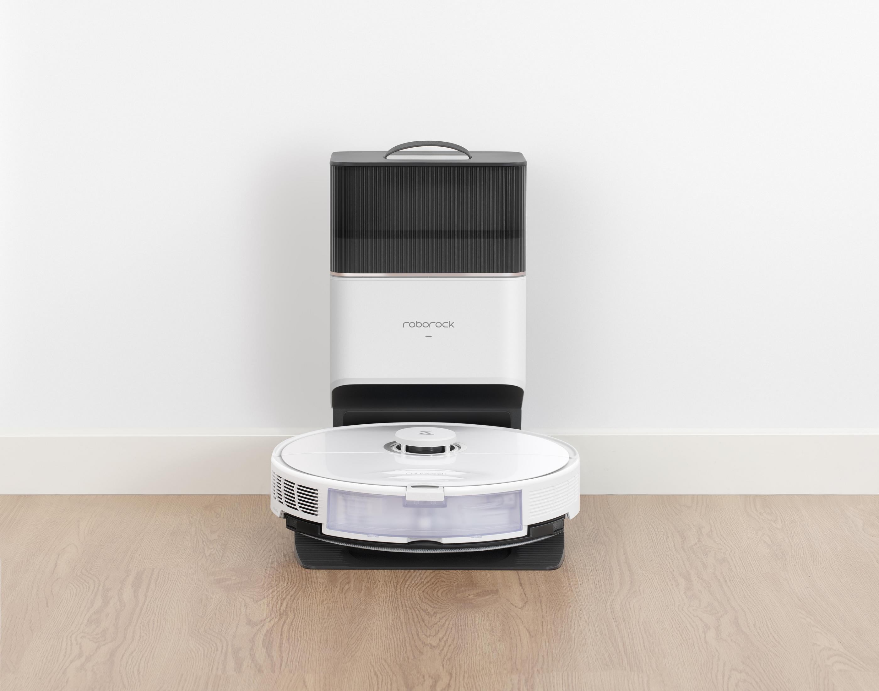Ein weißer und schwarzer Roboter-Staubsauger und seine Ladestation auf einem Holzboden.