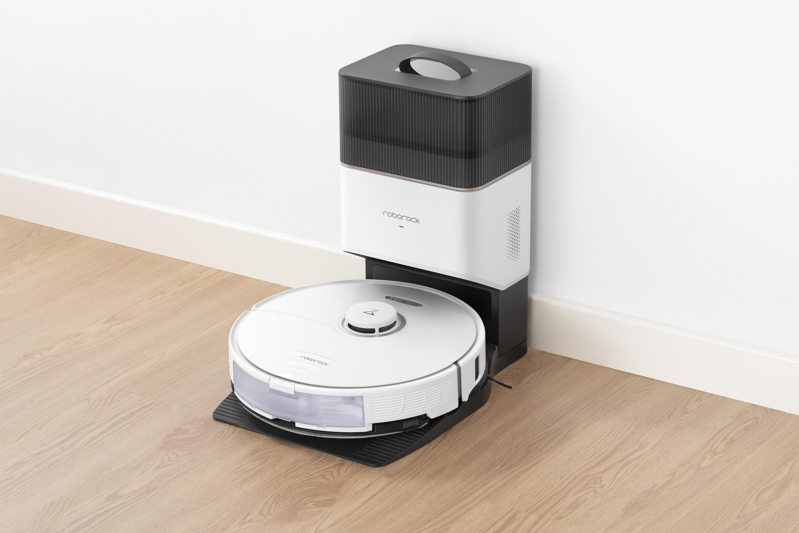 Weiß-schwarzer Roboter-Staubsauger auf schwarzer Basis, neben Ladestation auf Holzboden.