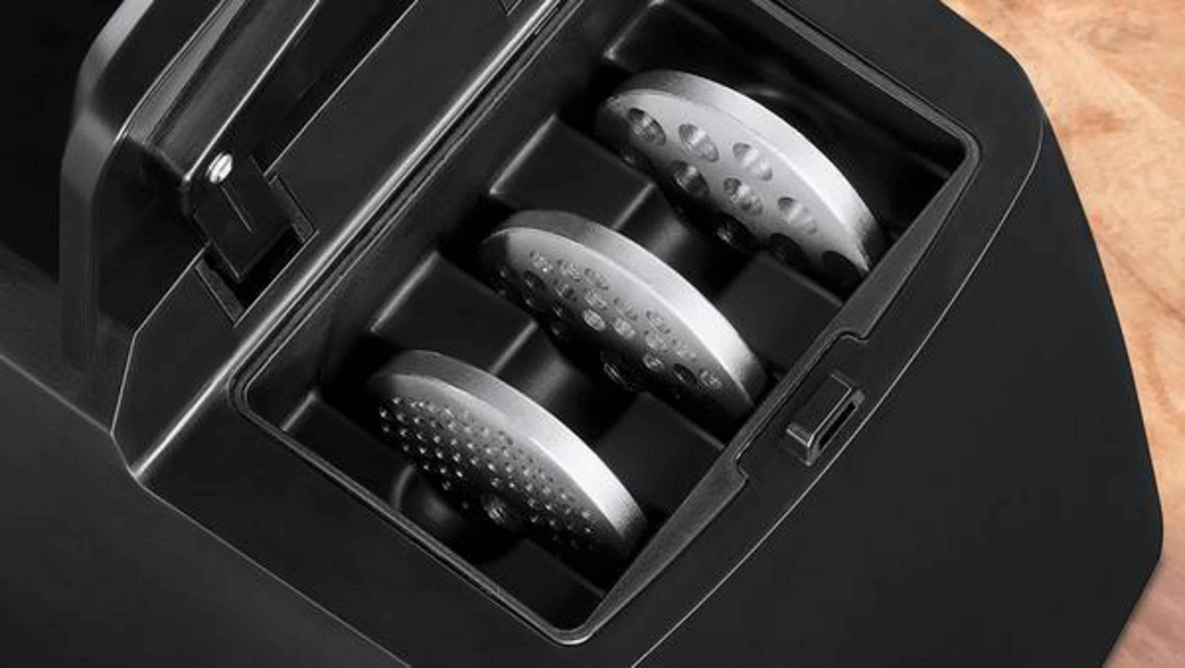 Zbliżenie czarnej komory zawierającej trzy srebrne nakładki do mielenia.