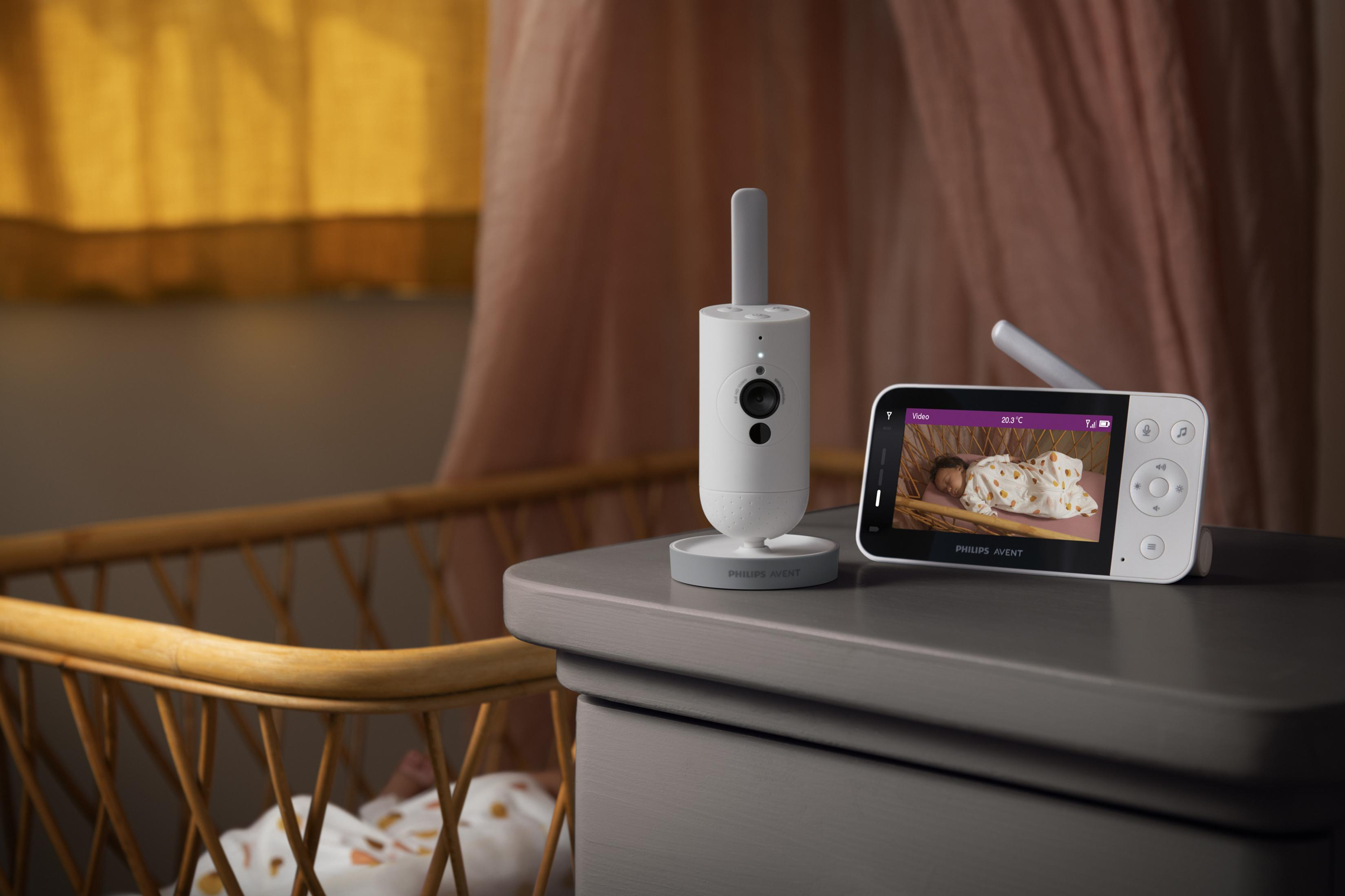Baby monitor su un comò, con bambino nella culla sullo sfondo.