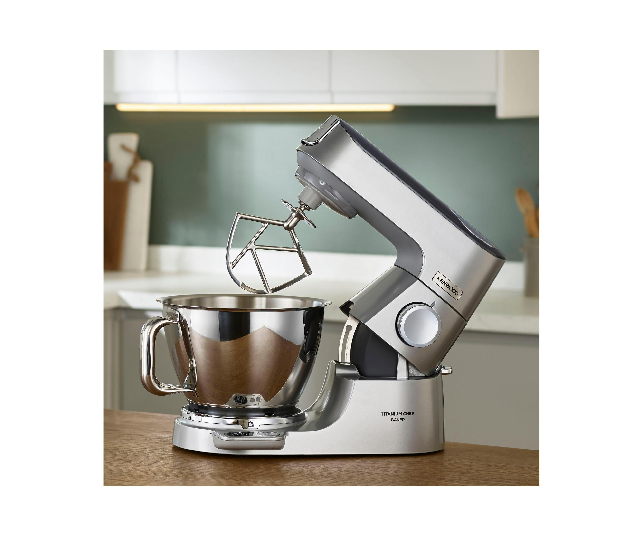 Srebrny mikser kuchenny z misą i przystawkami na drewnianej powierzchni.