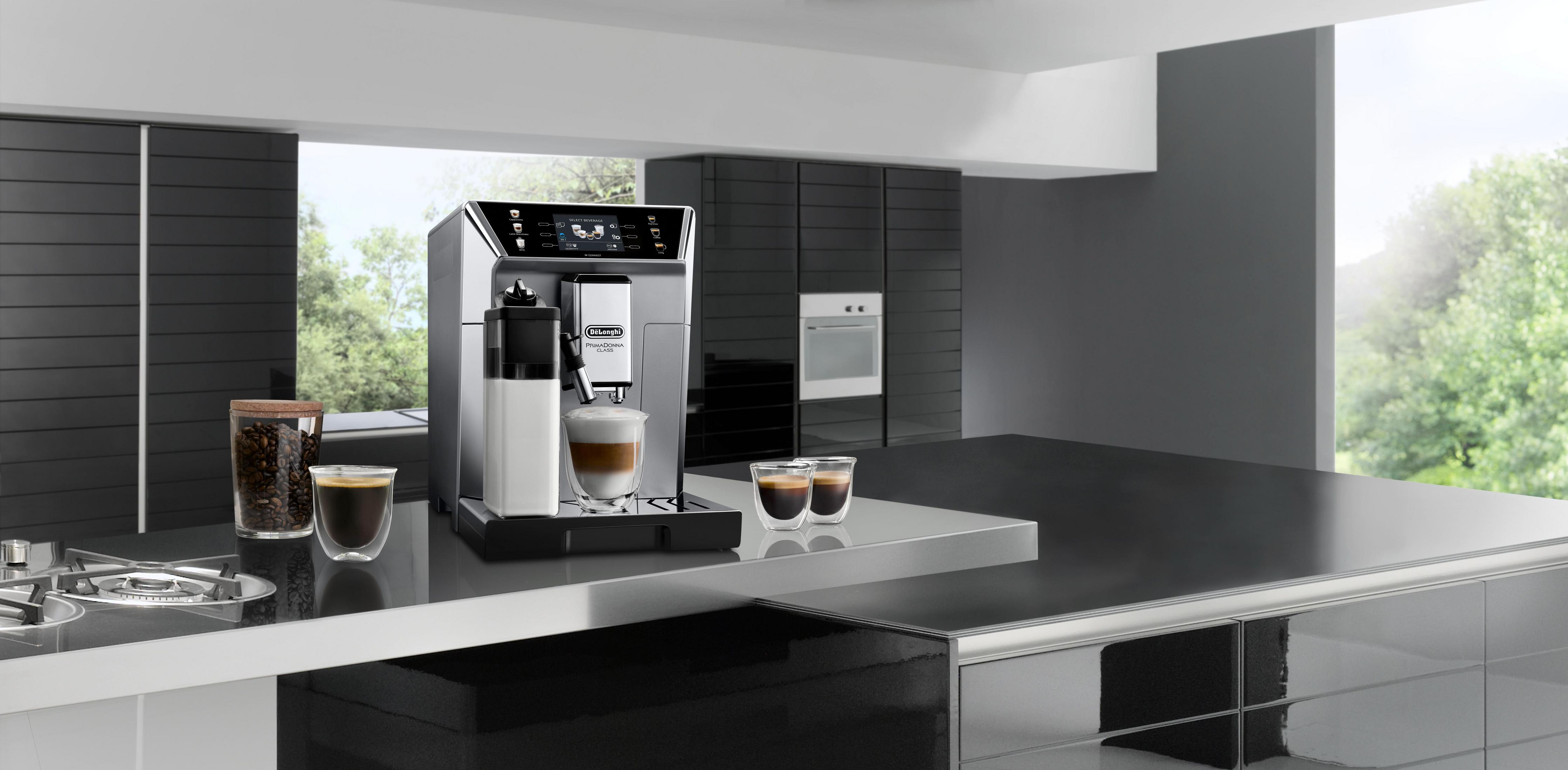 Silber-schwarze Kaffeemaschine mit einer Tasse, die Kaffee einschenkt. Auf der Theke befinden sich Kaffeebohnen und Tassen.