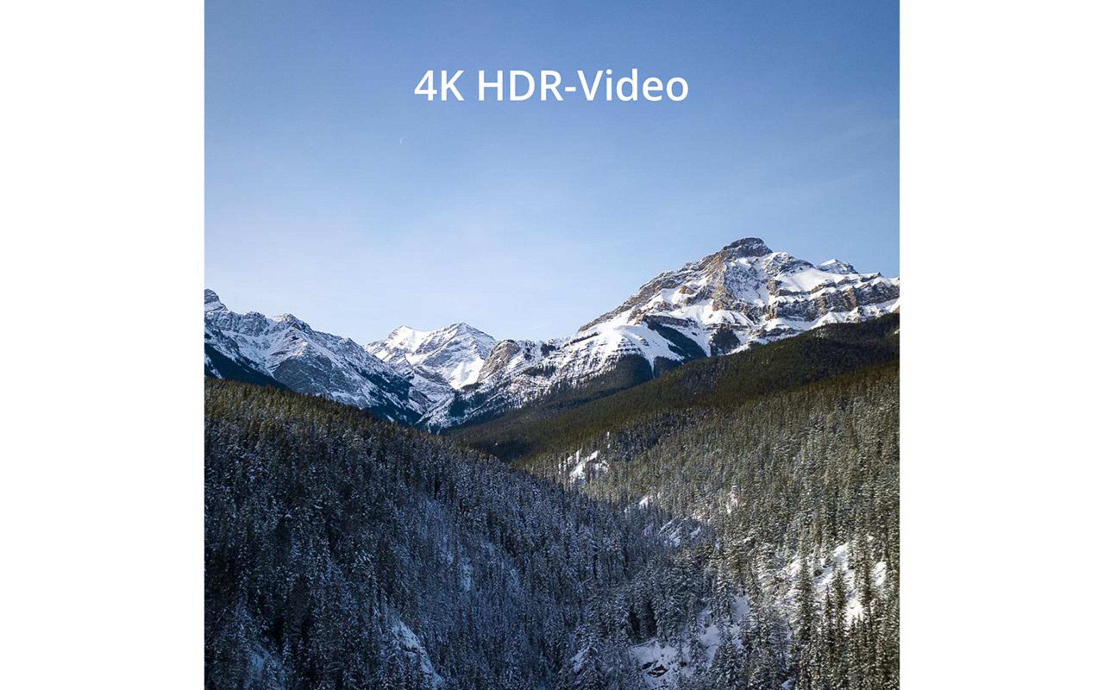 Schneebedeckte Berge und immergrüne Bäume unter blauem Himmel. Text: 4K HDR-Video.