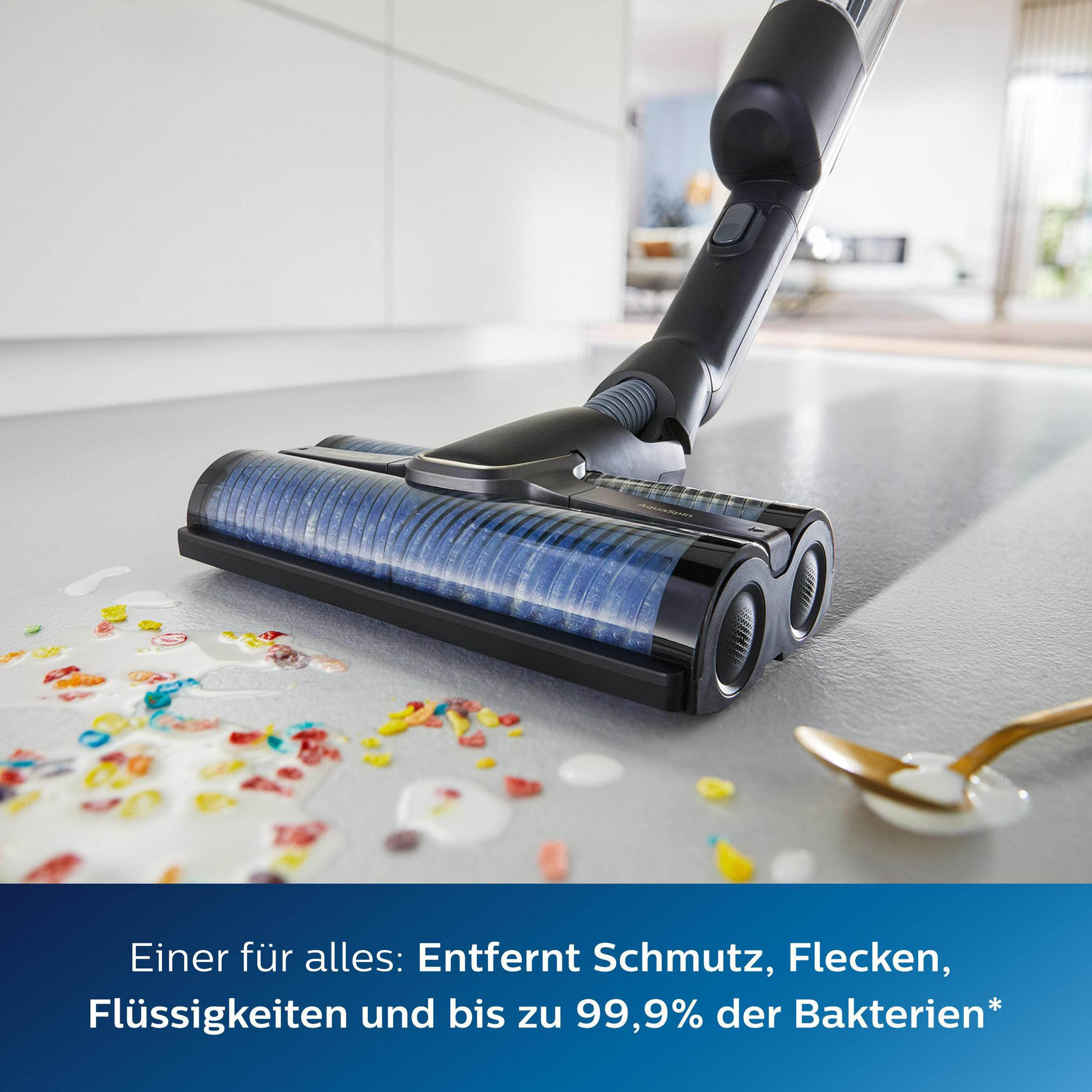 Ein Staubsauger reinigt einen verschütteten Fleck mit buntem Müsli. Ein Löffel liegt in der Nähe. Der Hintergrund ist weiß.