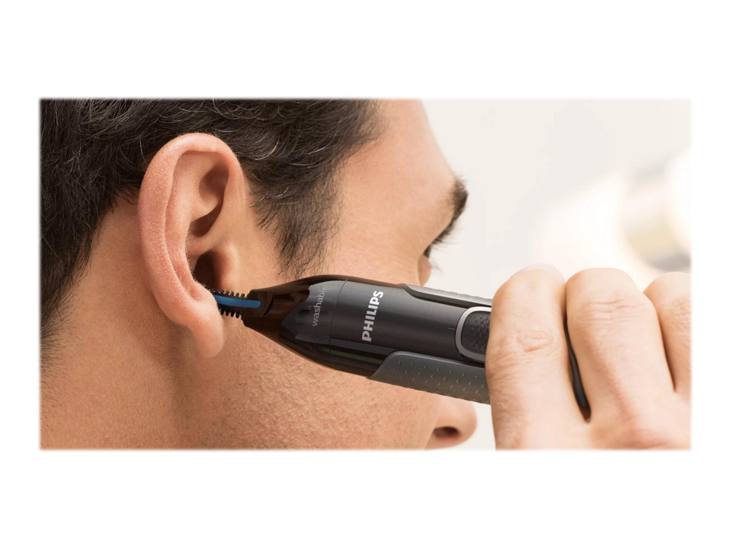 Mężczyzna używa trymera do włosów w nosie Philips. Trymer jest w uchu mężczyzny, zbliżenie.
