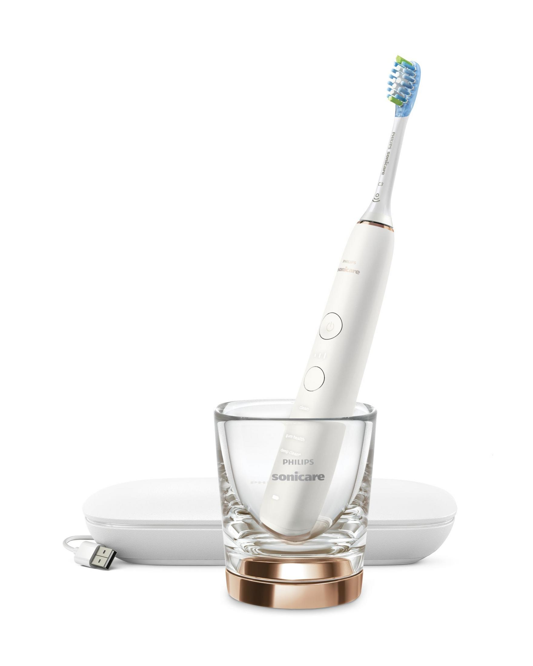 Spazzolino elettrico bianco in un bicchiere. Base di ricarica e cavo USB.