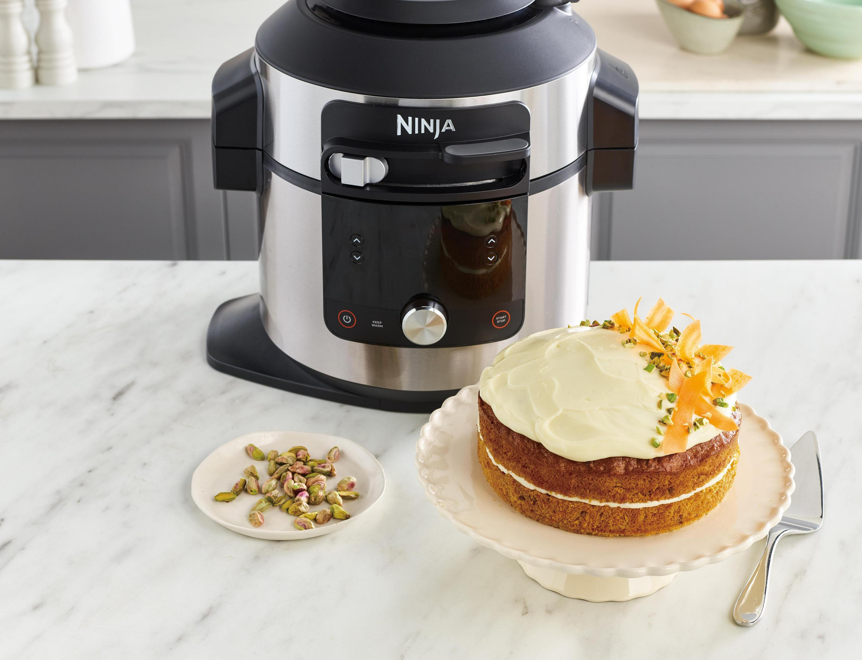 Ninja Küchengerät neben Kuchen, Pistazien und Servierutensilien.