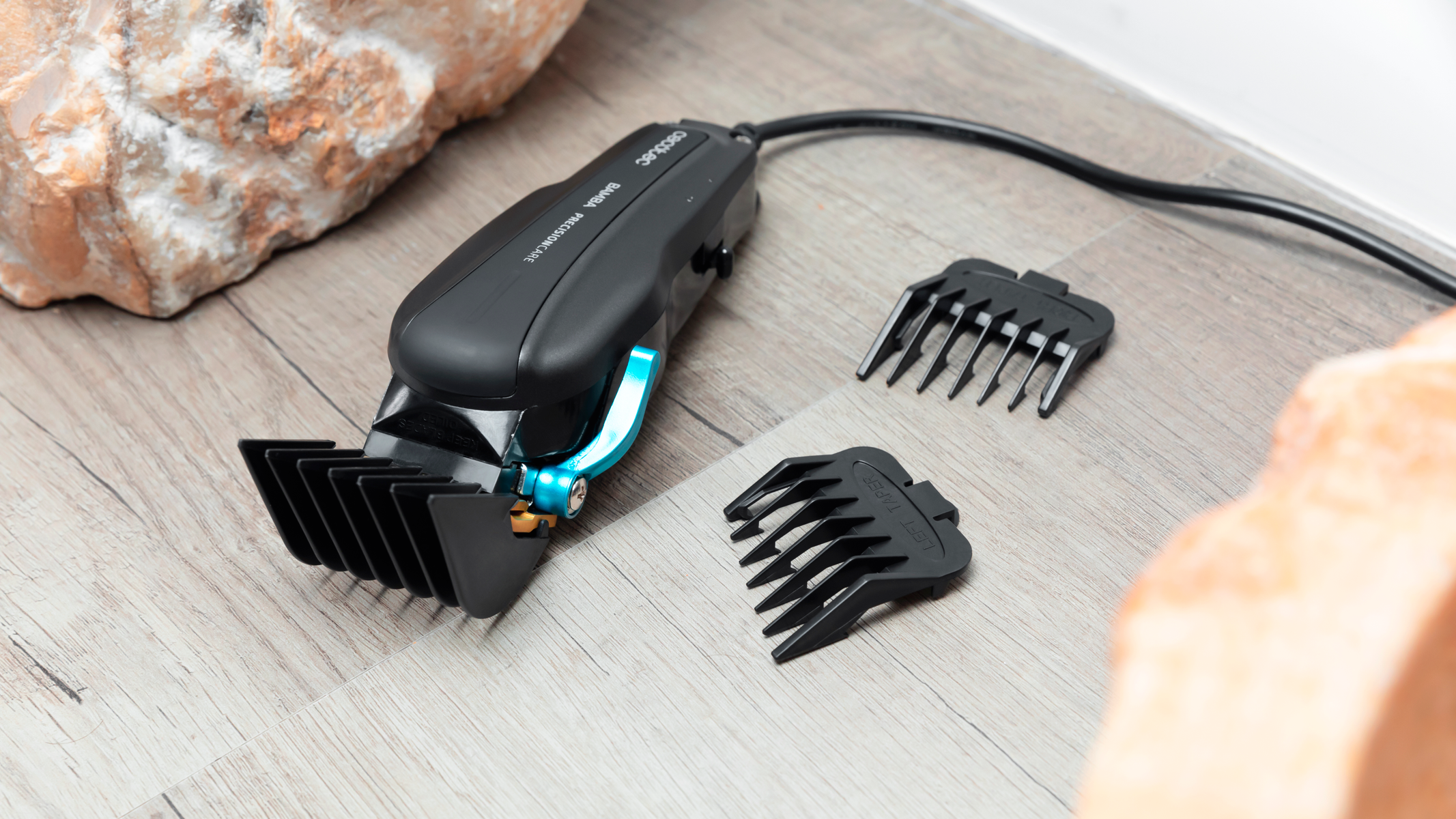 Cortapelos eléctrico y tres accesorios sobre una superficie de madera, primer plano.