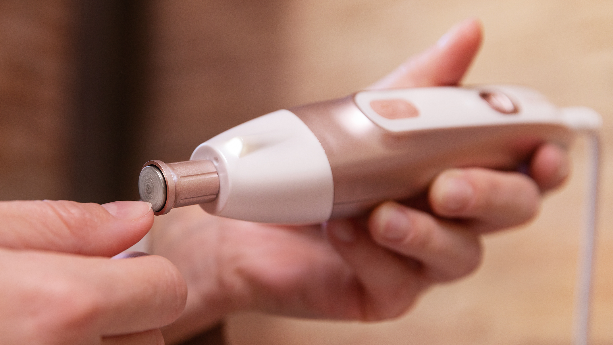 Ręka używająca szlifierki do paznokci. To małe, przenośne urządzenie z obrotową głowicą szlifującą.