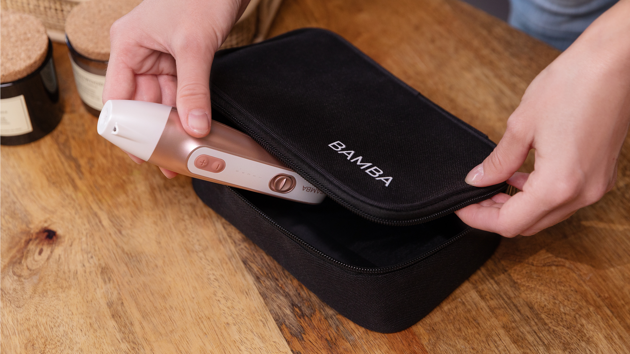 Dłonie otwierają czarne etui z różowo-białym urządzeniem do pielęgnacji.