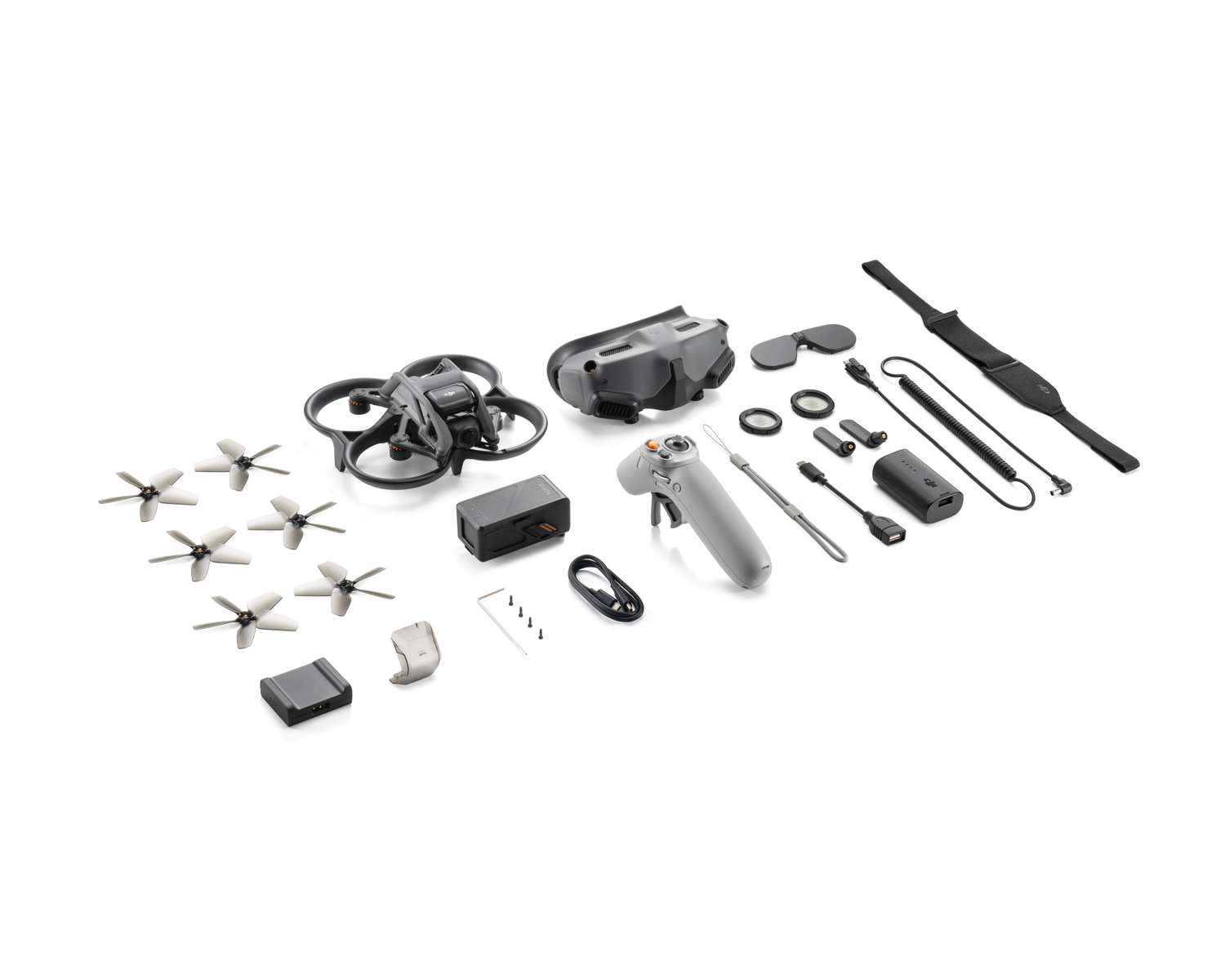 Kit de dron con dron, gafas, controlador, batería y accesorios, todo sobre superficie blanca.