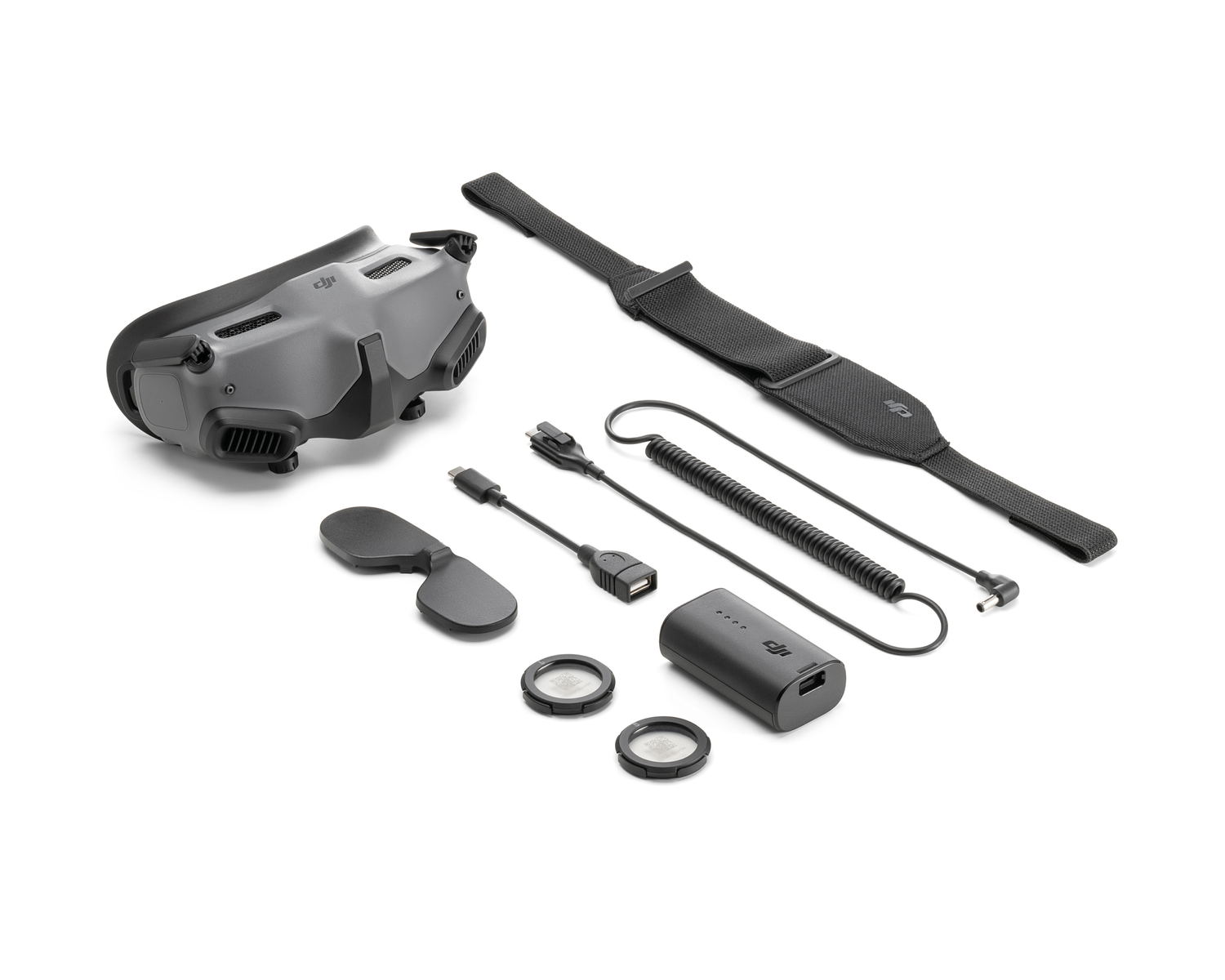 Auriculares VR con accesorios: batería, cables y protectores de lentes, todo sobre una superficie blanca.