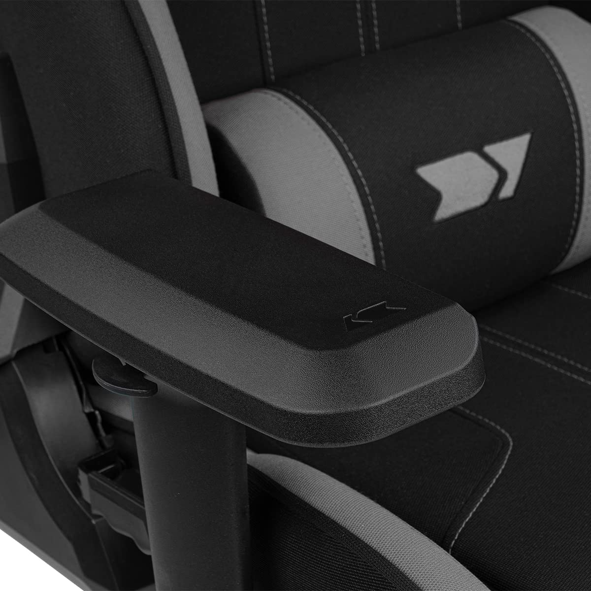 Primer plano de un reposabrazos de silla gaming negro y gris con un logotipo.