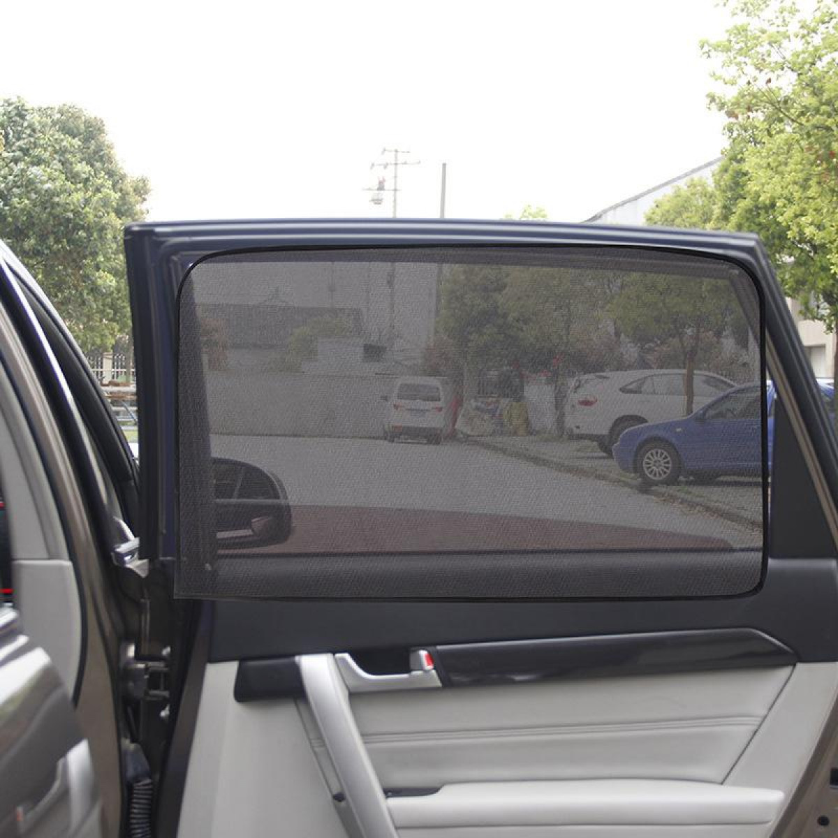Eine Autotür mit einem an der Scheibe angebrachten Sonnenschutz. Die Scheibe ist getönt.