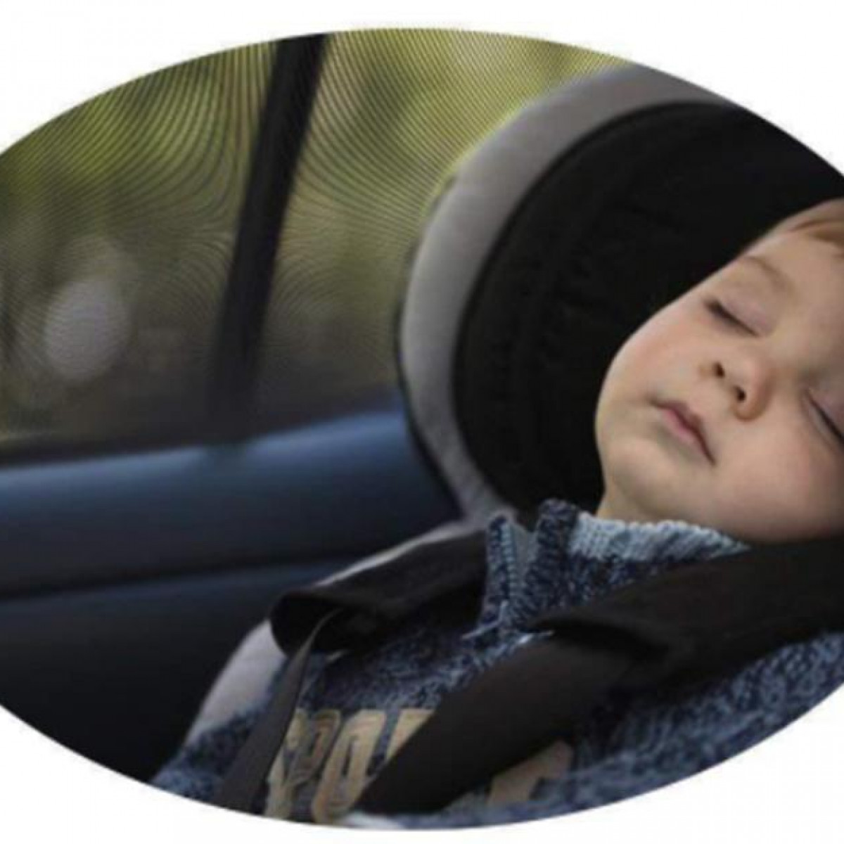 Ein schlafendes Kind in einem Autositz. Das Kind ist angeschnallt, das Fenster hat einen Sonnenschutz.