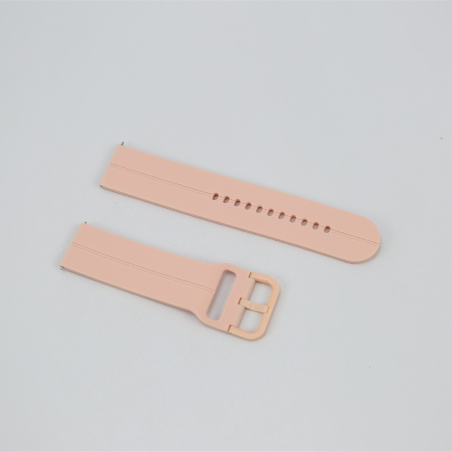 Zwei hellrosa Uhrenarmbänder liegen auf einer hellgrauen Oberfläche. Eines hat eine Schnalle befestigt.