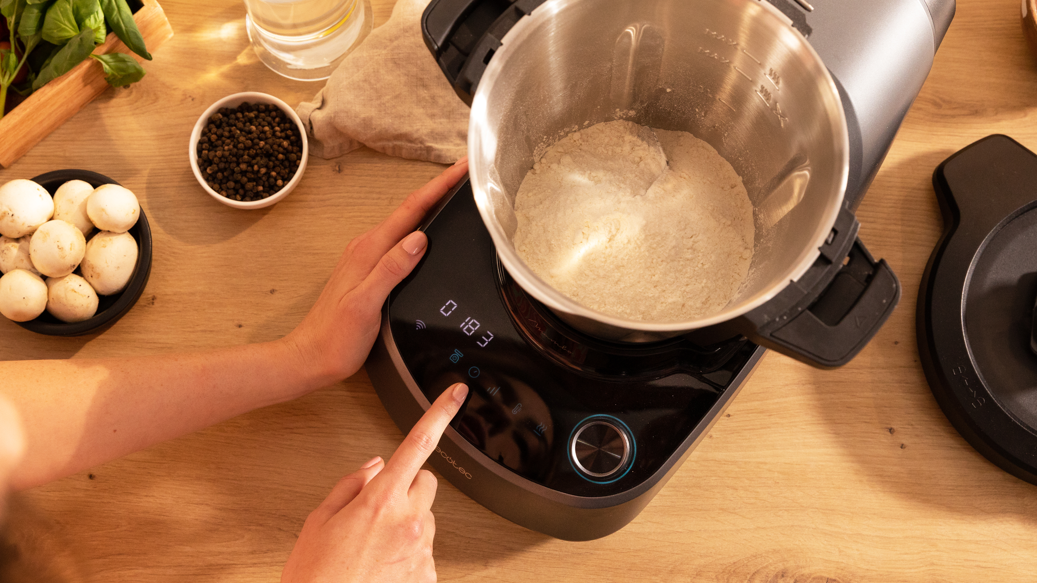 Mano presionando un botón en un procesador de alimentos con ingredientes cerca.