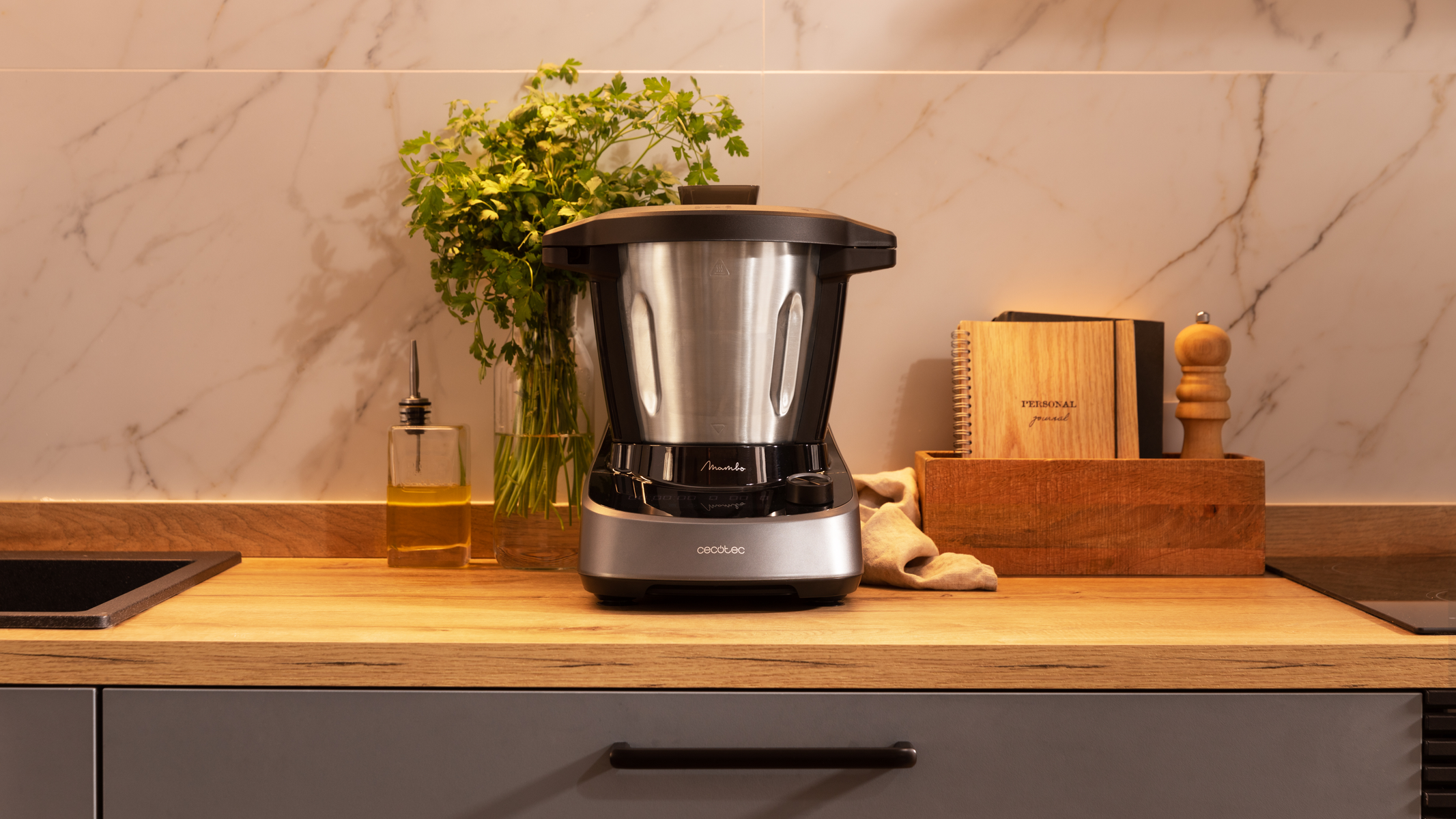 Encimera de cocina con procesador de alimentos, aceite de oliva, hierbas y accesorios de madera.