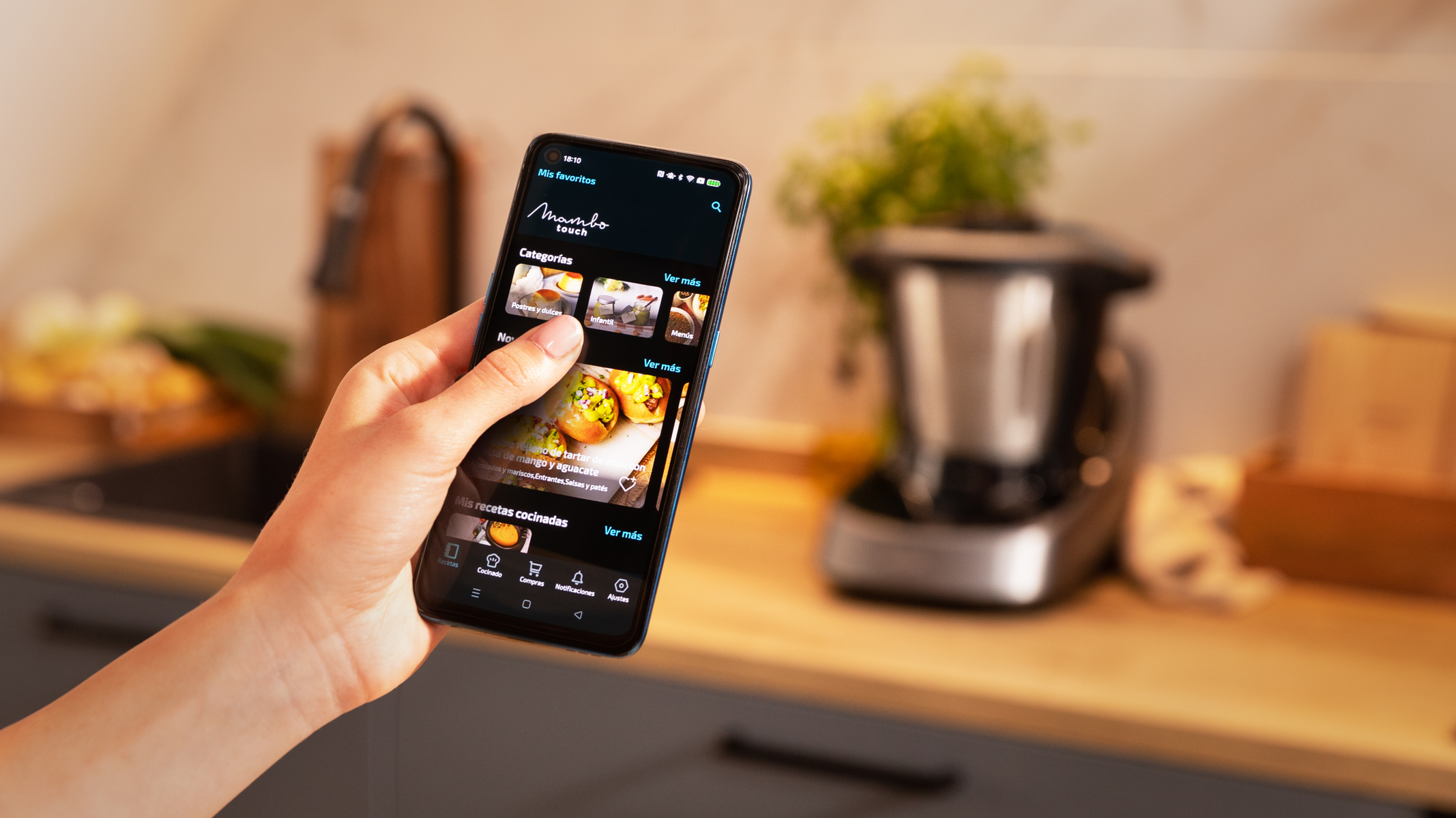 Una persona sostiene un smartphone que muestra la interfaz de una app de cocina.