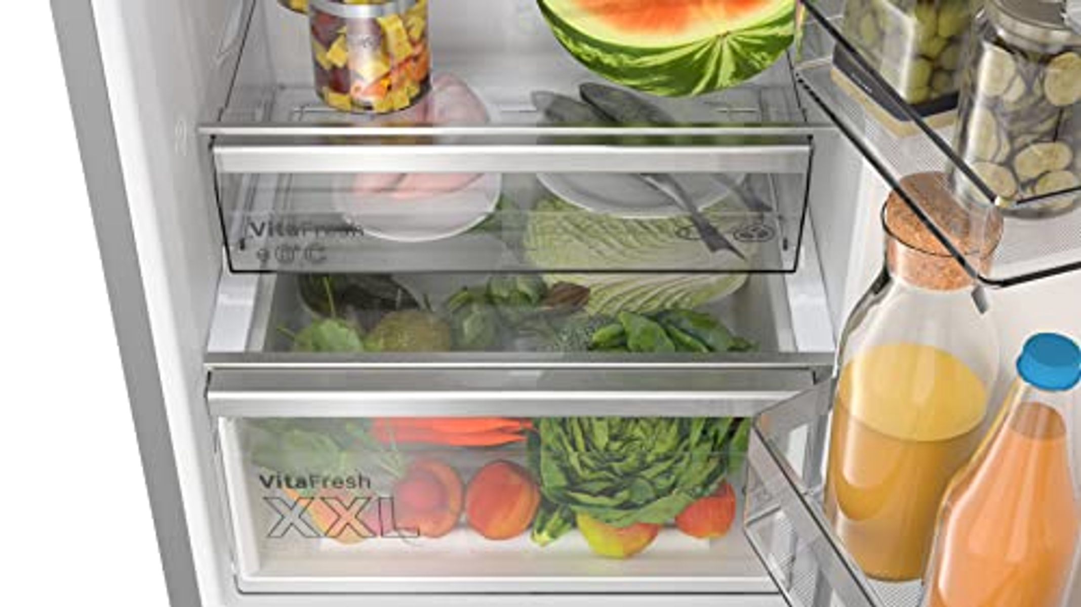 Im Kühlschrank: klare Schubladen mit Gemüse und Obst. Gläser und Flaschen an der Seite.