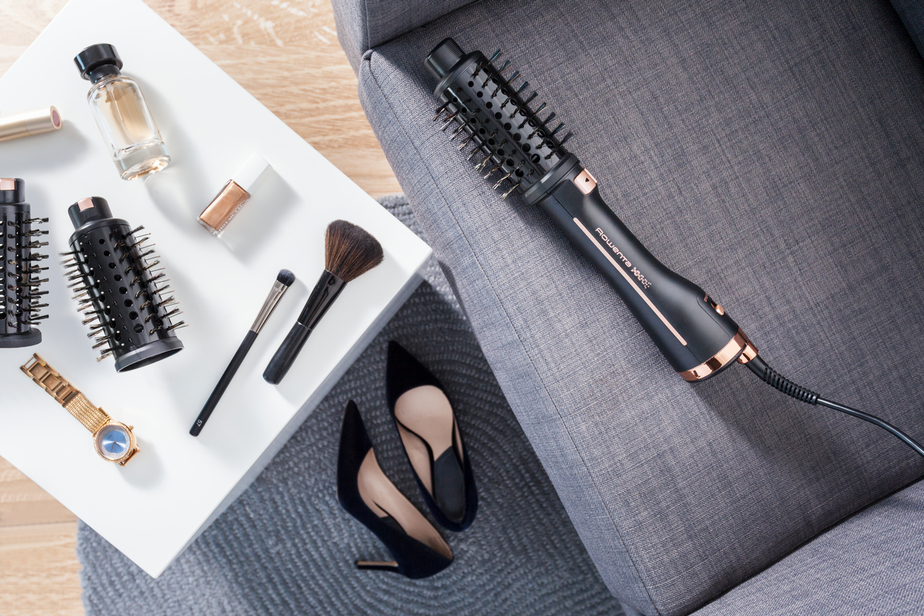 Narzędzia do stylizacji włosów: szczotka do suszenia włosów, pędzle do makijażu, zegarek, perfumy i szpilki.