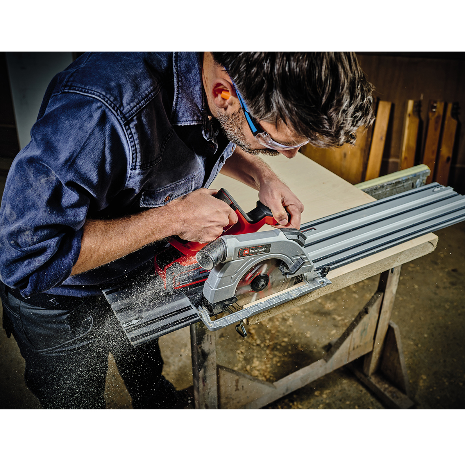Mężczyzna używa piły tarczowej do cięcia drewna. Noszone są okulary ochronne i ochrona słuchu.