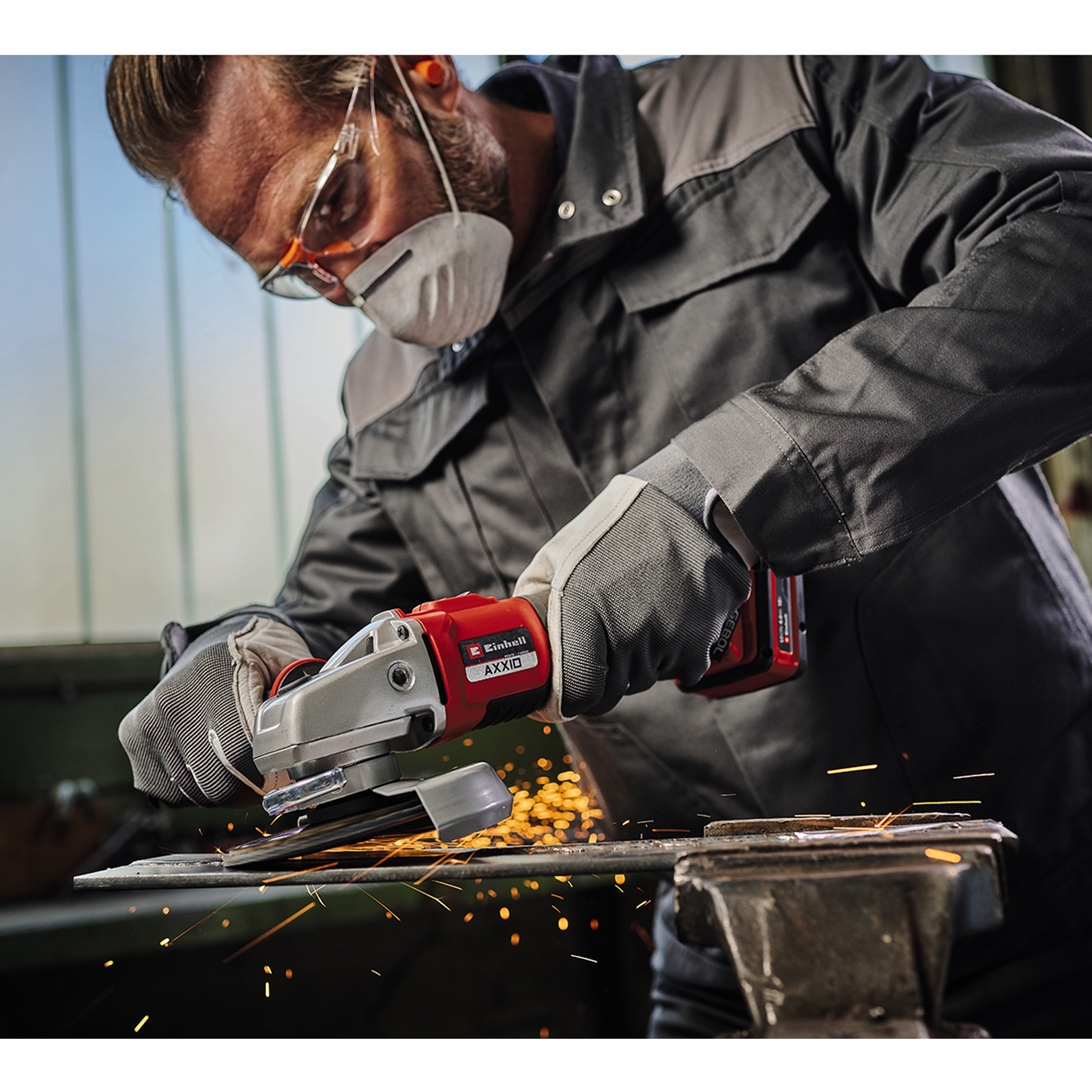 Mężczyzna używa szlifierki, lecą iskry. Ma maskę i rękawice.