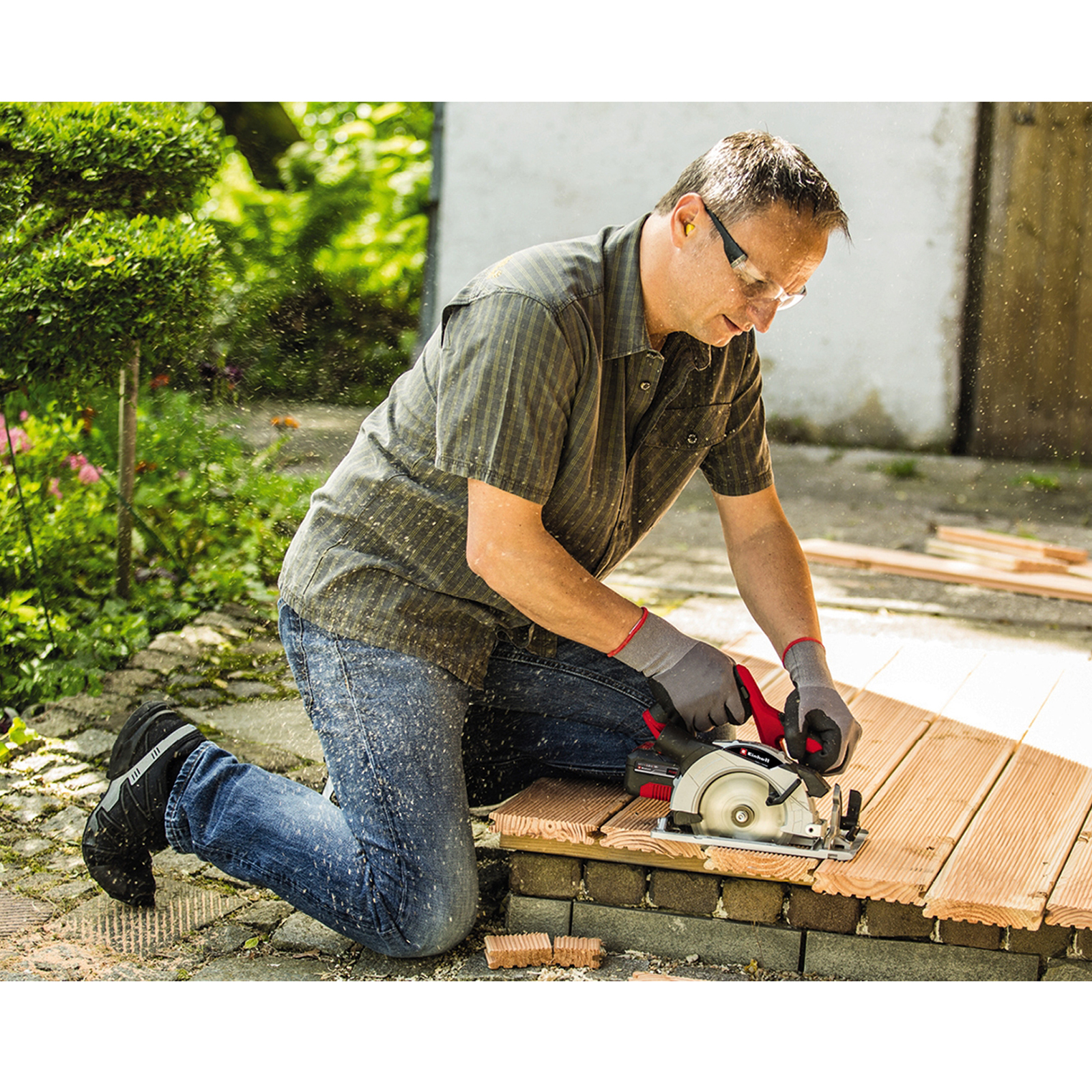 Mężczyzna tnie drewno piłą tarczową, wióry lecą.