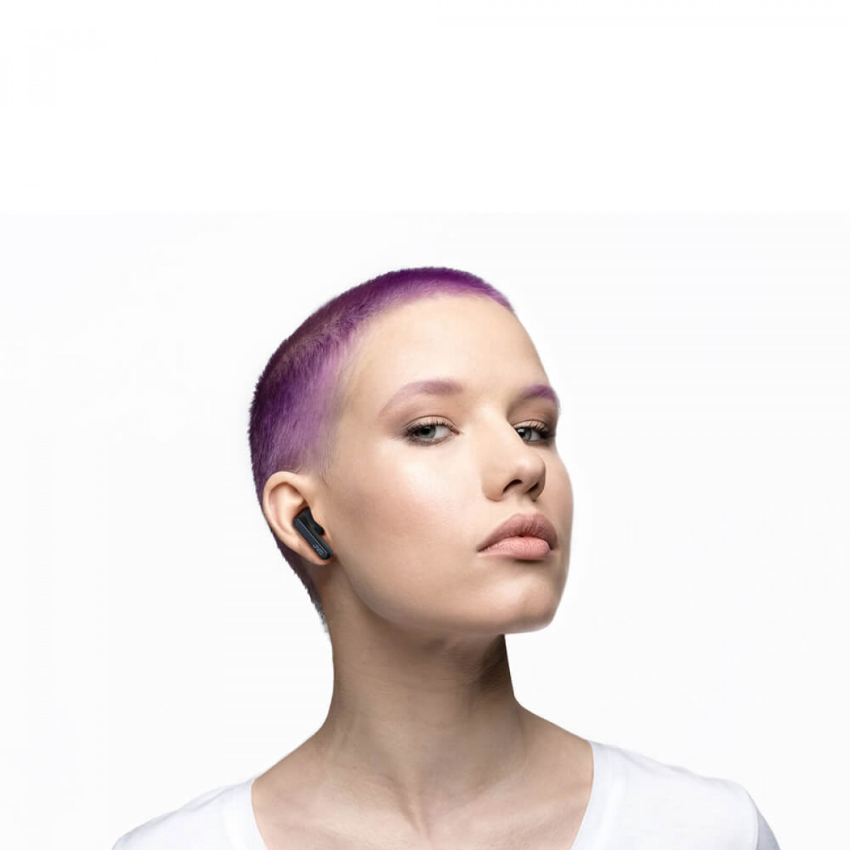 Kobieta z fioletowymi włosami w czarnej słuchawce, patrząca w kamerę, białe tło.