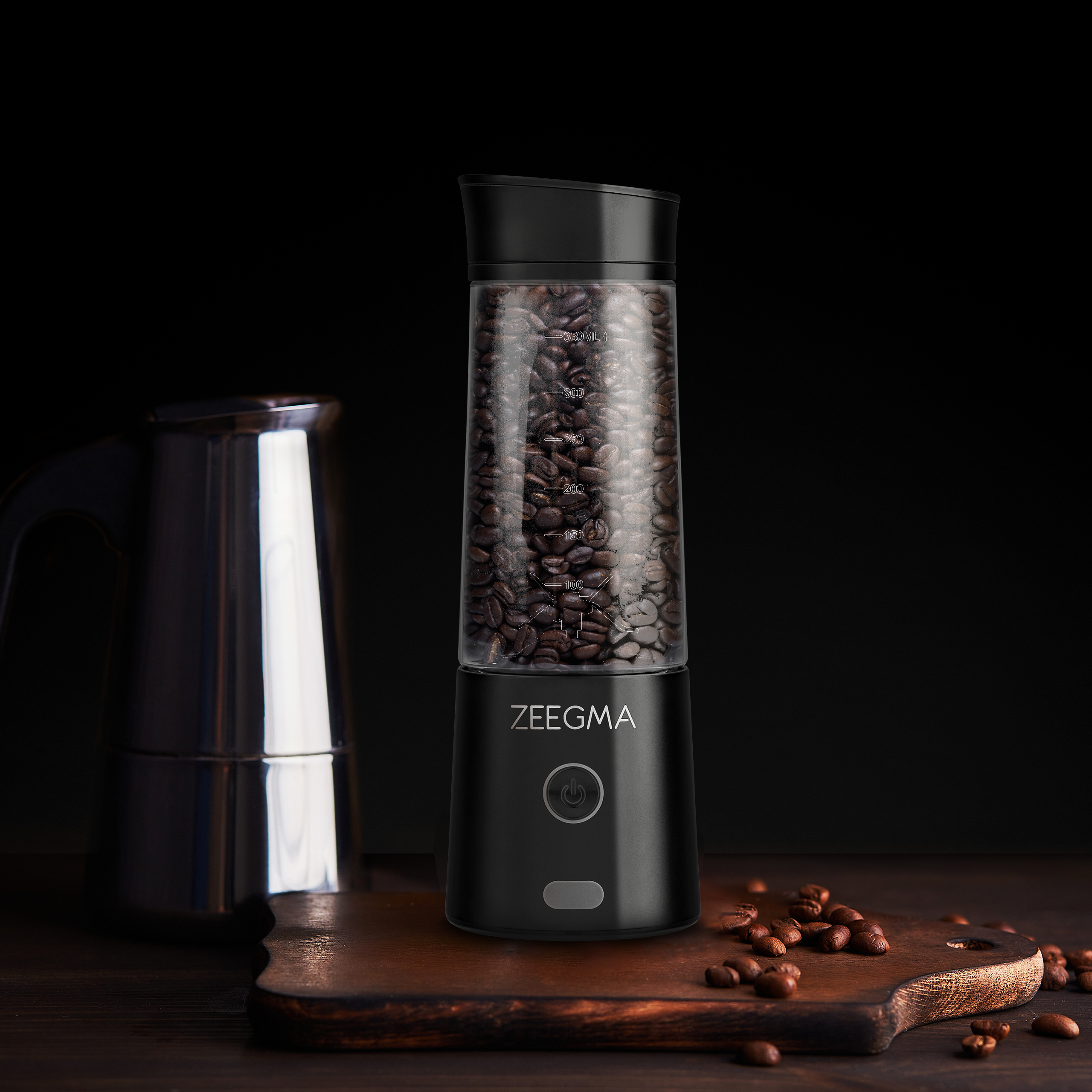 Czarny młynek do kawy z ziarnami, kawiarka na drewnianej desce.