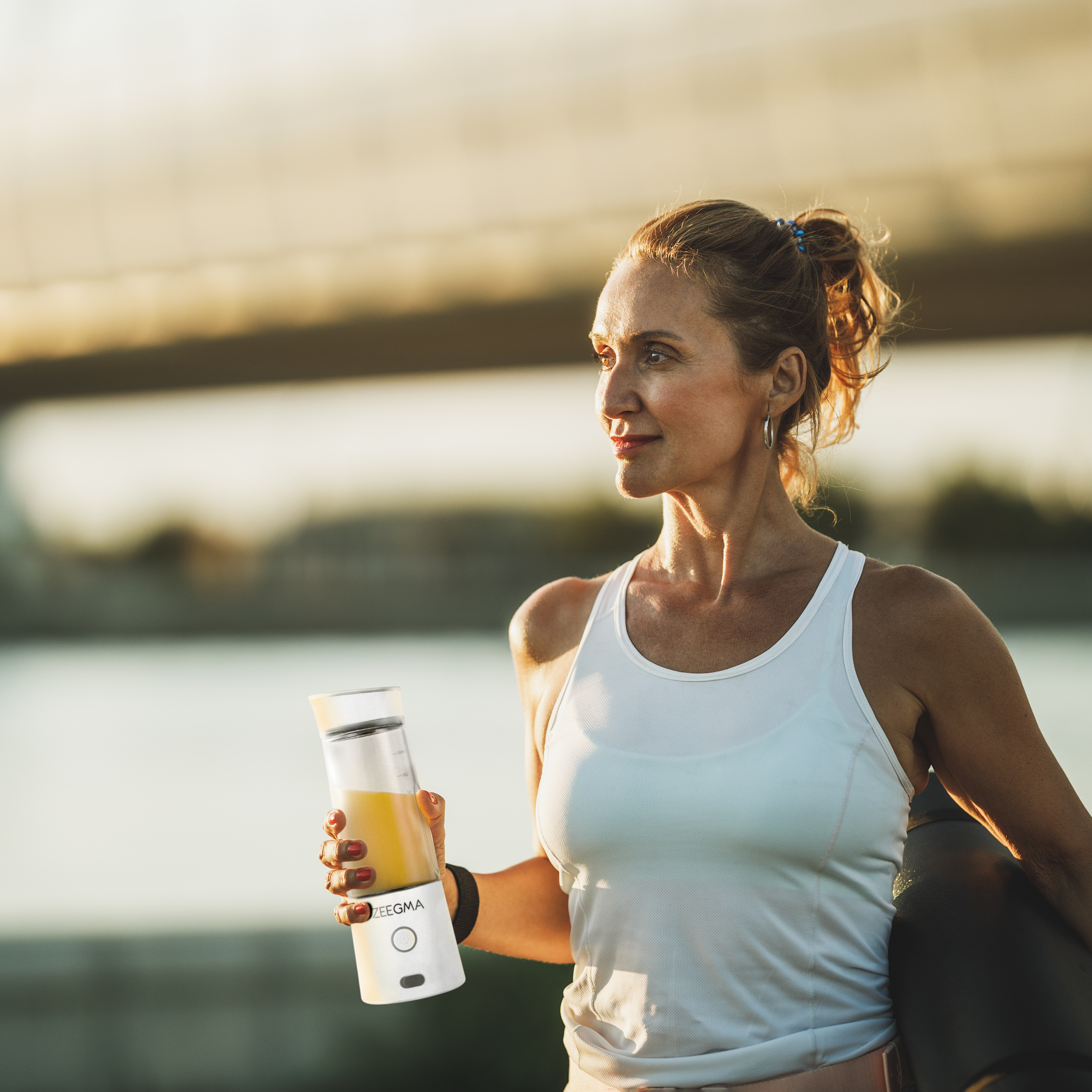 Kobieta trzymająca butelkę blendera w pobliżu zbiornika wodnego.