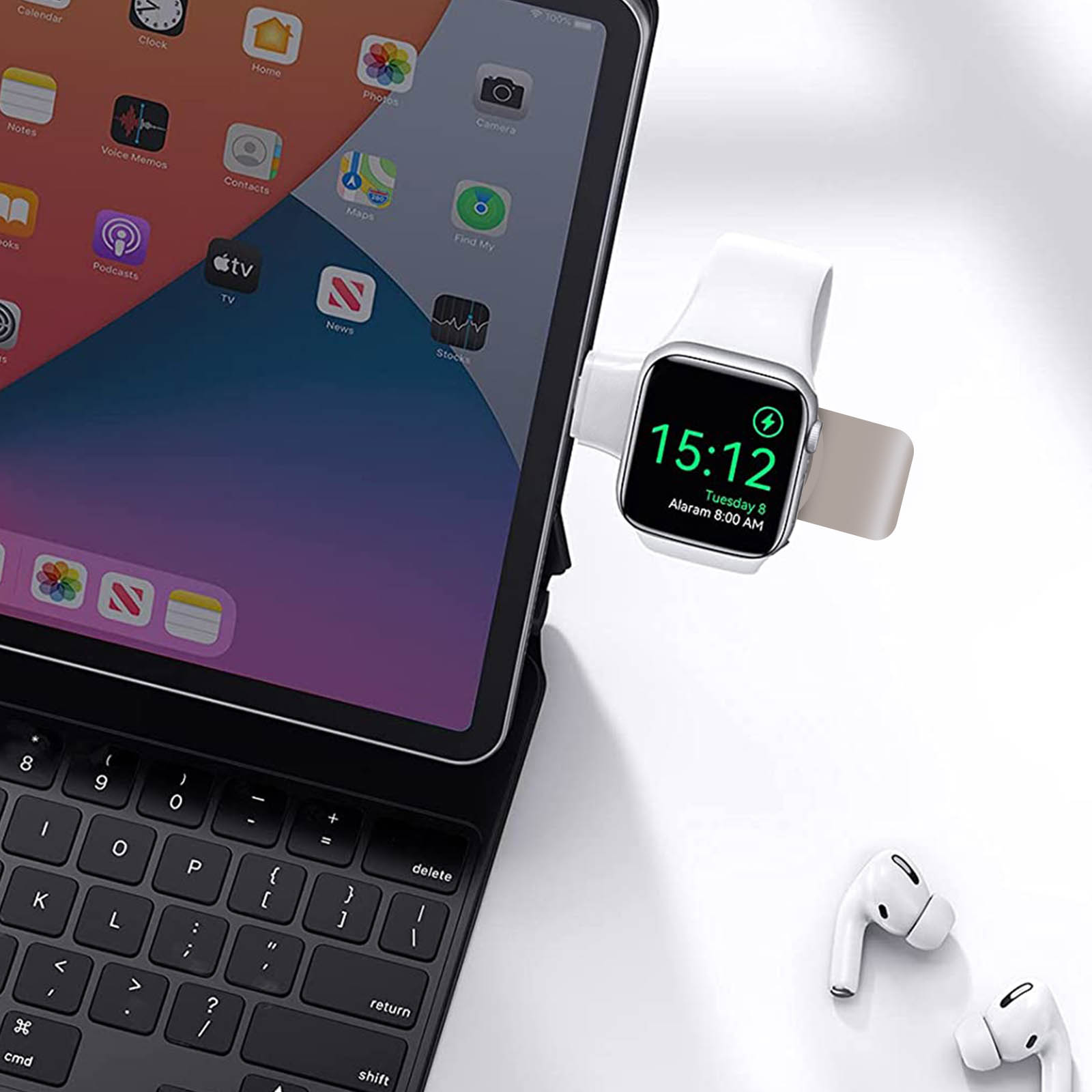 Tablet mit Tastatur und Apple Watch Ladung, mit Ohrhörern auf weißem Untergrund.