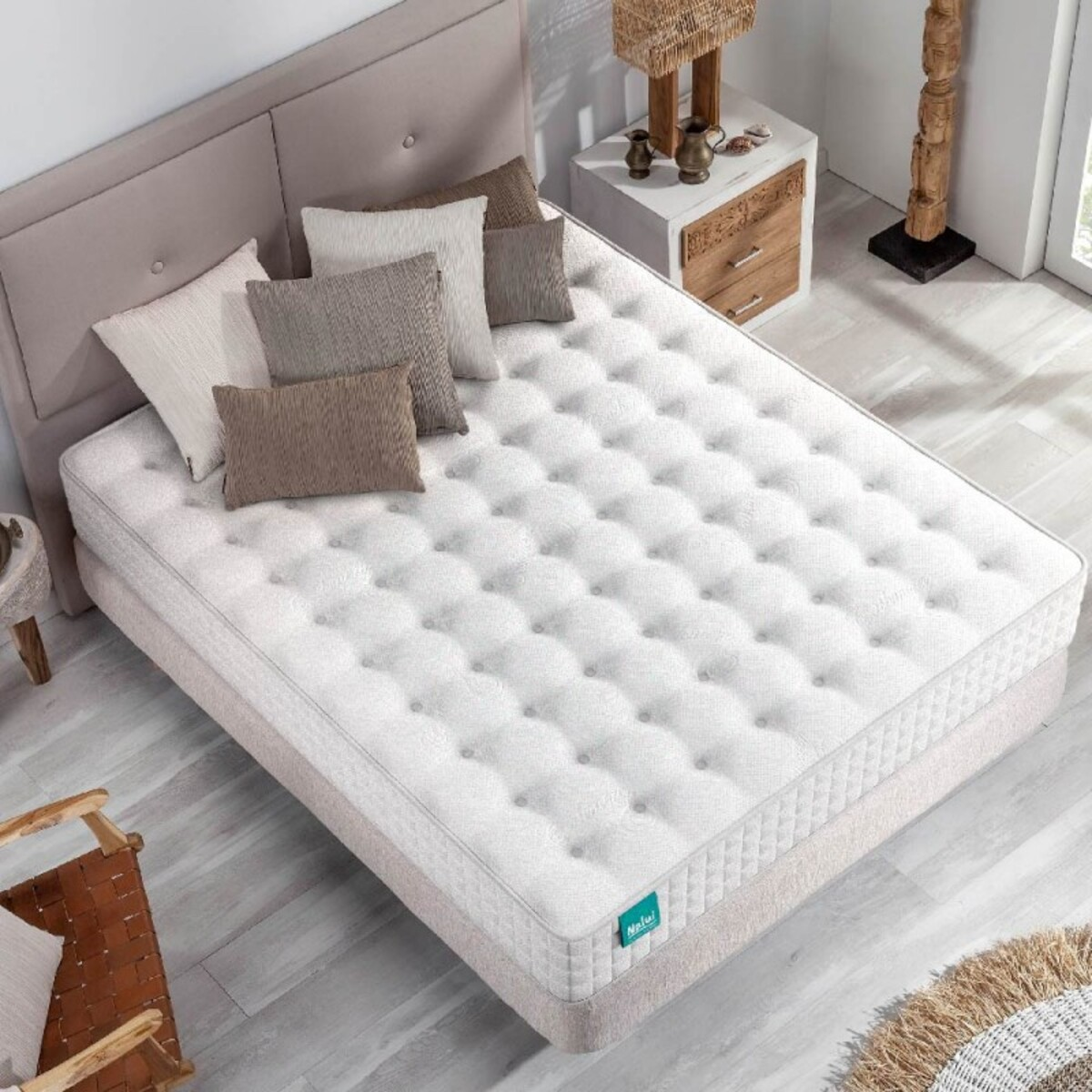 Colchón doble en una cama, con almohadas, mesita de noche y decoración de madera.