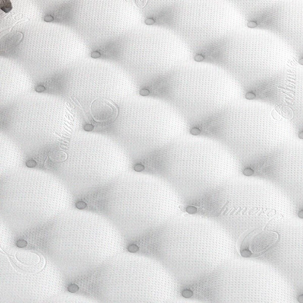 Colchón blanco con capitoné. Patrón de diamantes, superficie texturizada y etiquetas cosidas.