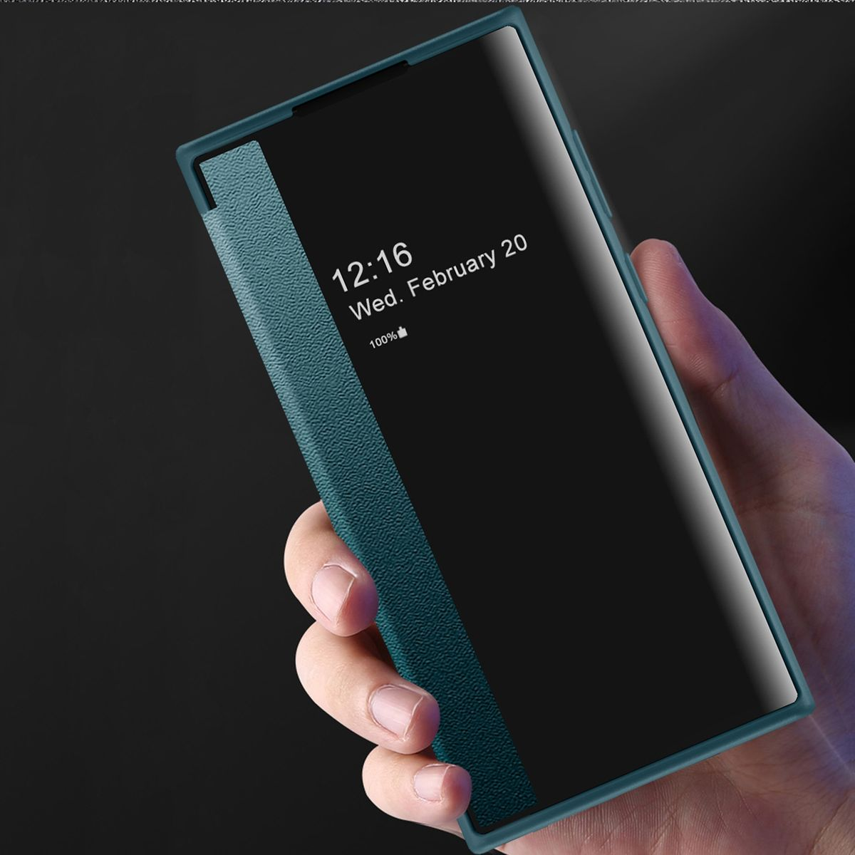 Hand, die eine teal-farbene Handyhülle hält, auf dem Datum und Uhrzeit angezeigt werden. Dunkler Hintergrund. Geschlossen.