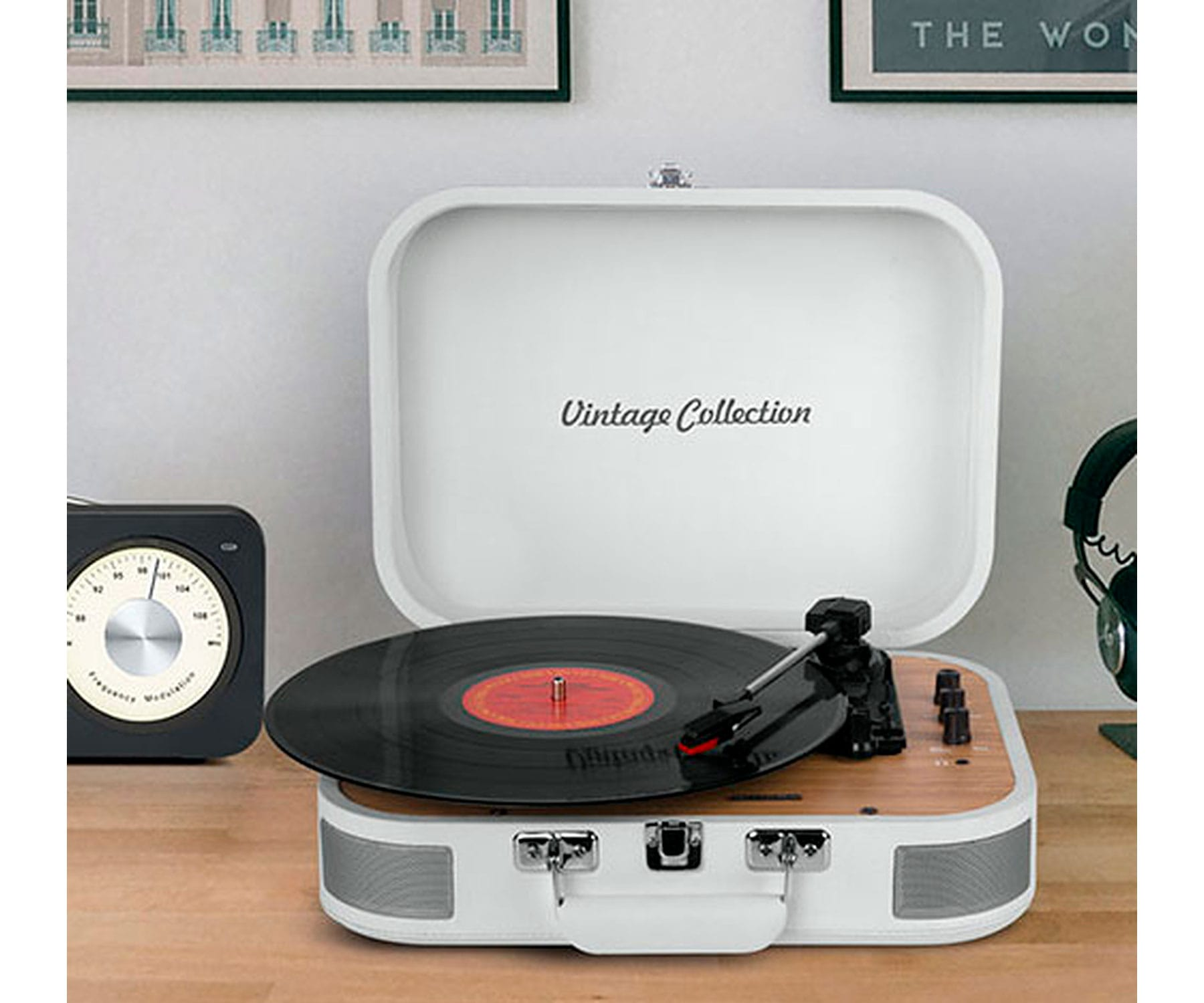 Un tocadiscos vintage blanco con un disco encima, y una radio y auriculares cerca.