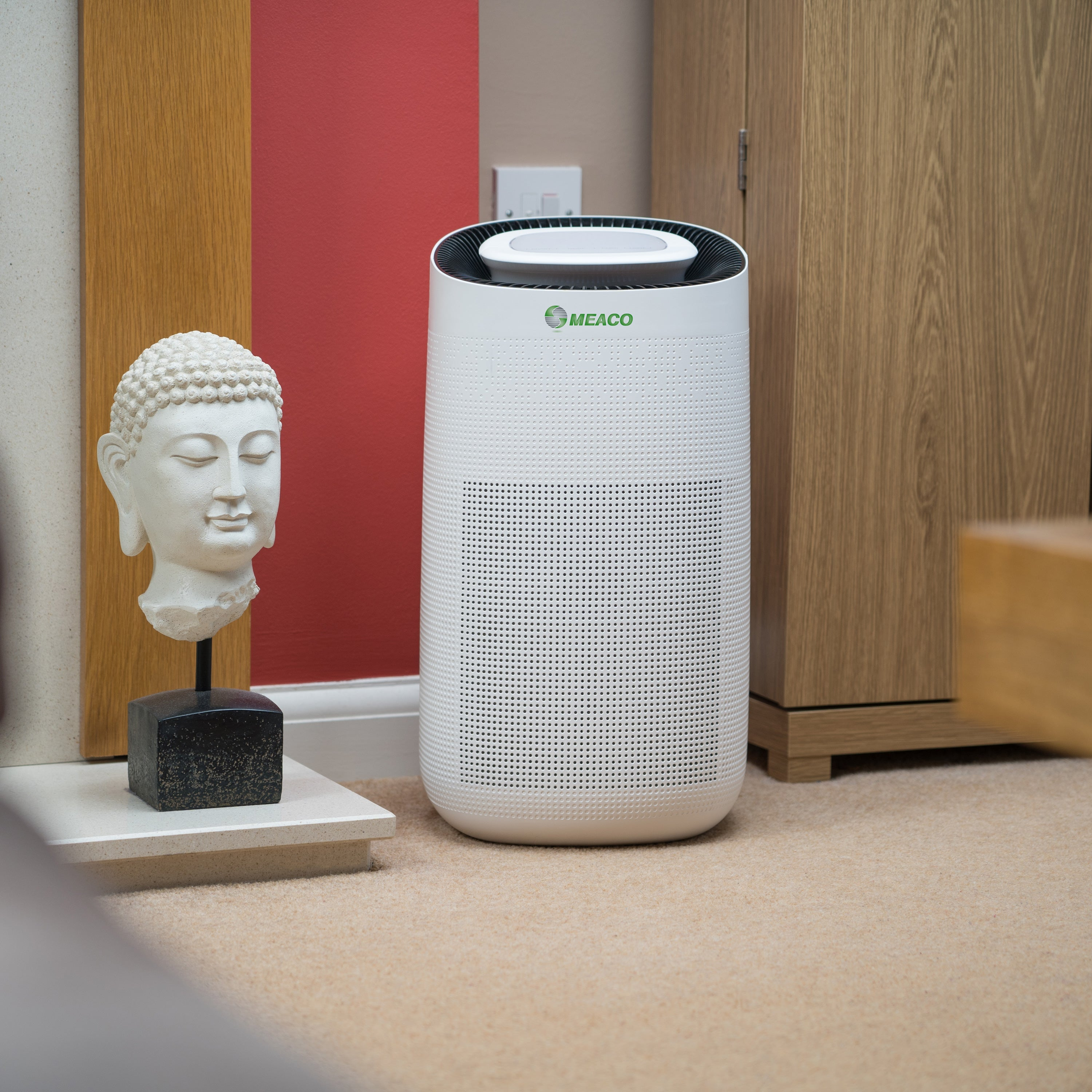 Weißer Luftreiniger, Buddha-Statue und Holzschrank in einem Raum.
