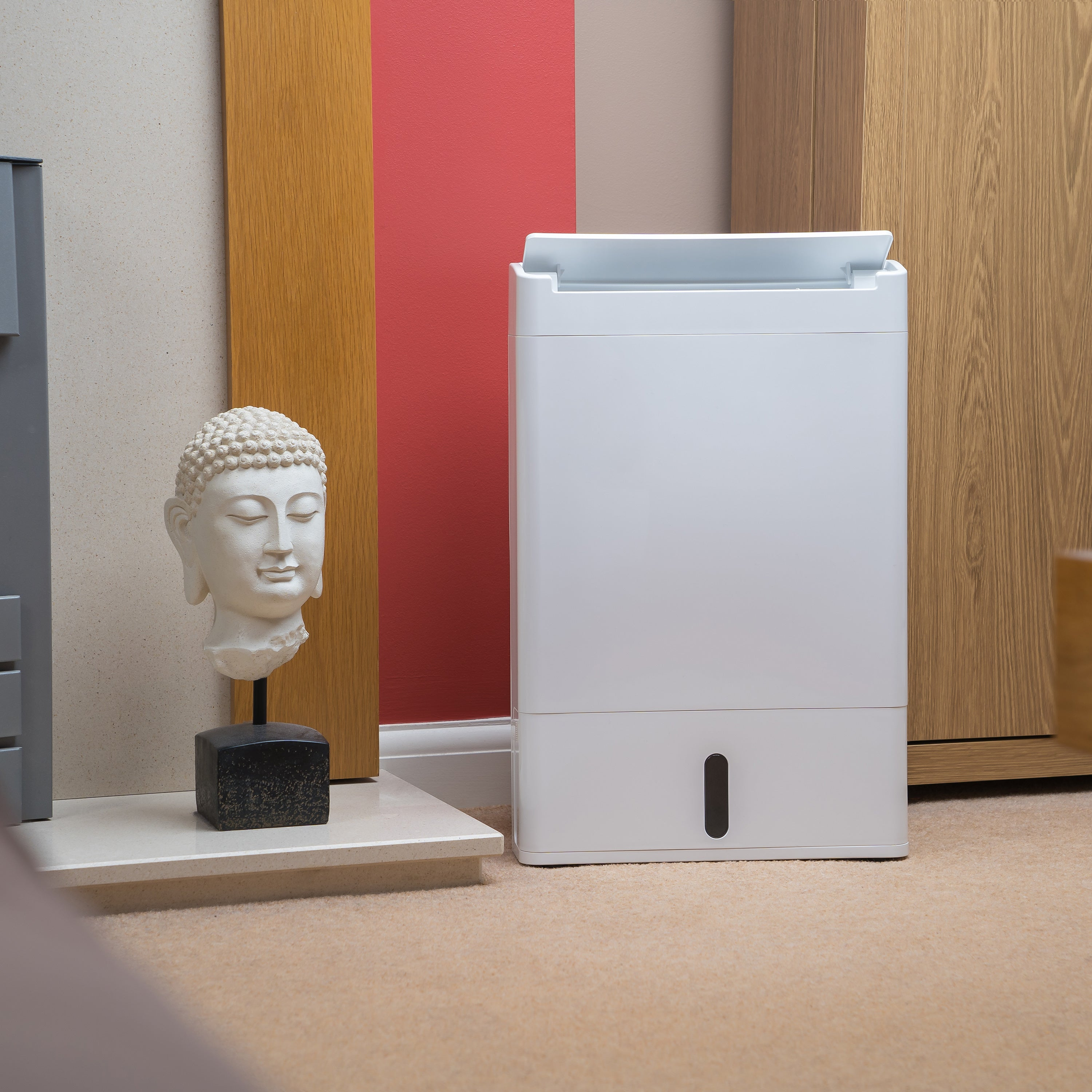 Biały osuszacz, biała statua głowy Buddy i ściany w kolorze drewna.