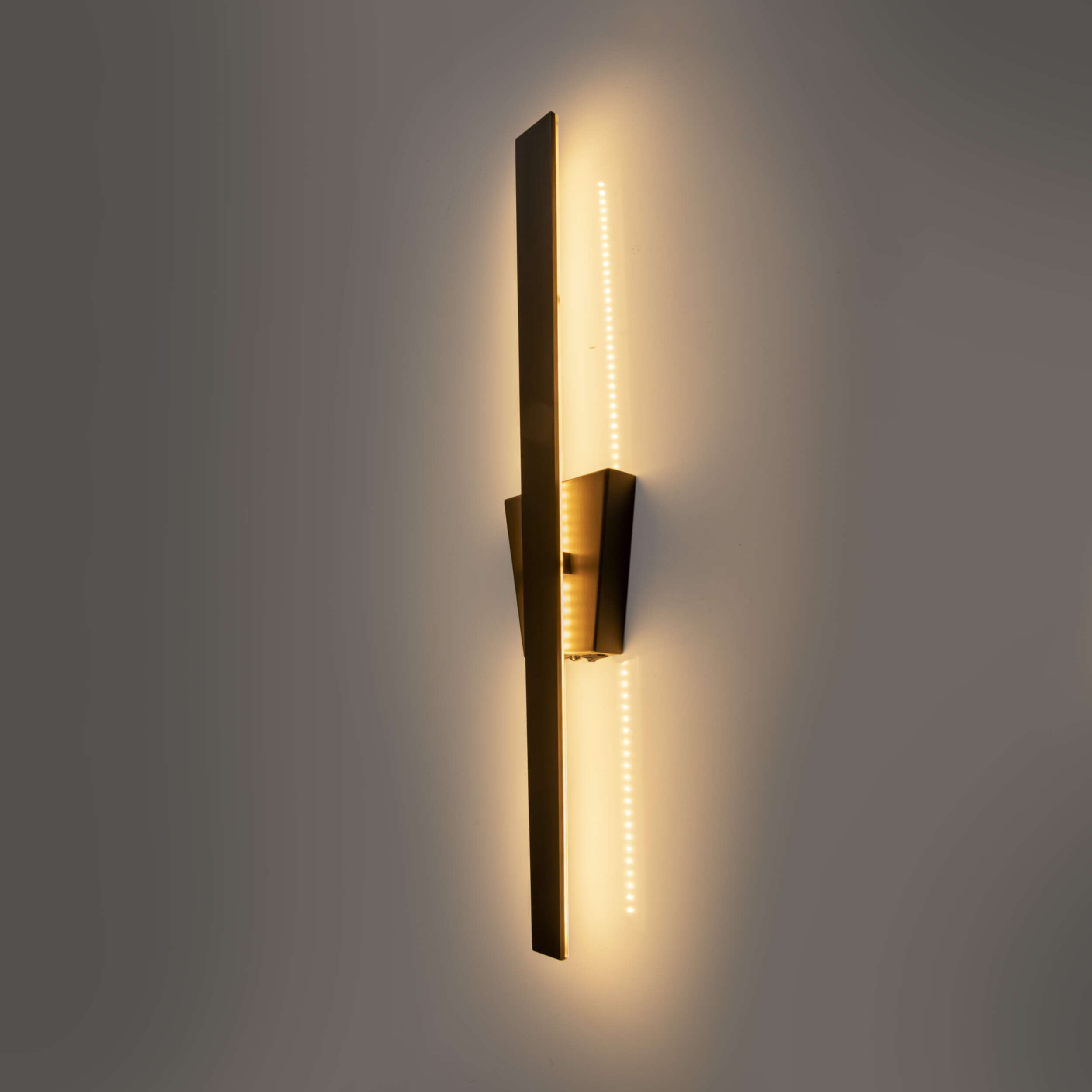 Moderne Wandlampe mit vertikalem Design und LED-Beleuchtung, an hellgrauer Wand montiert.