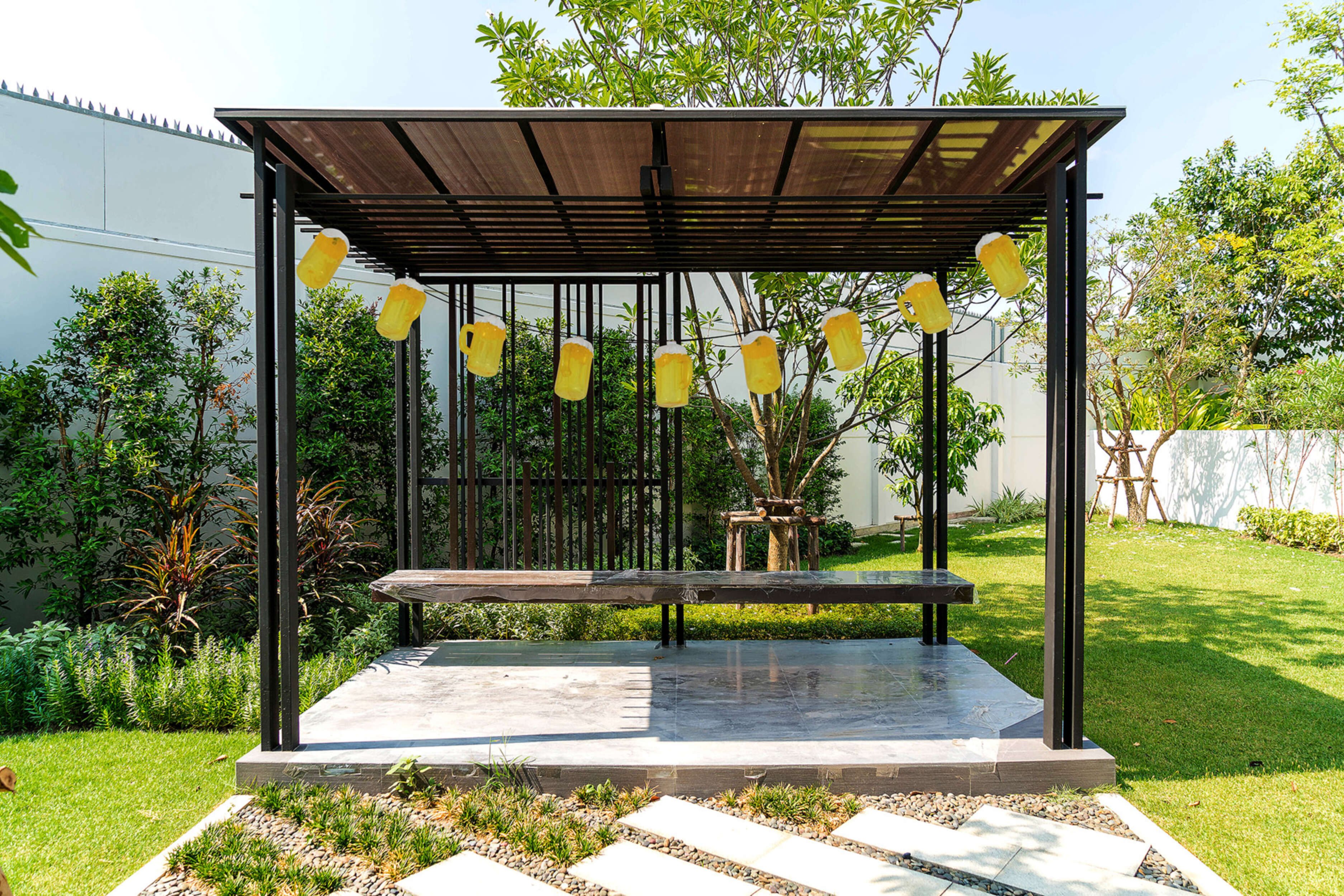 Pavillon mit hängenden Bierkrügen auf Gras. Bäume und Gebäude im Hintergrund.