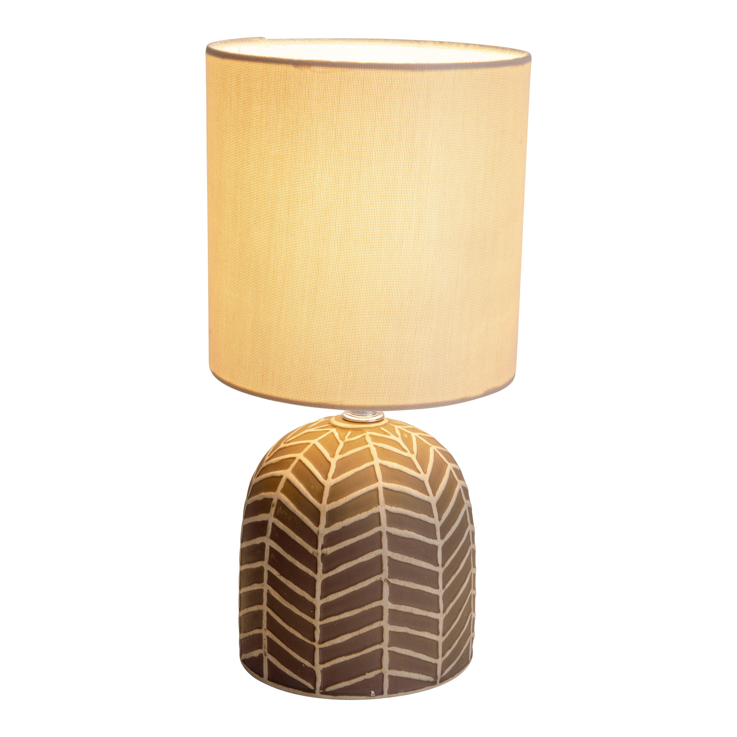 Eine Lampe mit einem braunen Sockel mit weißen Mustern und einem beigefarbenen Lampenschirm.