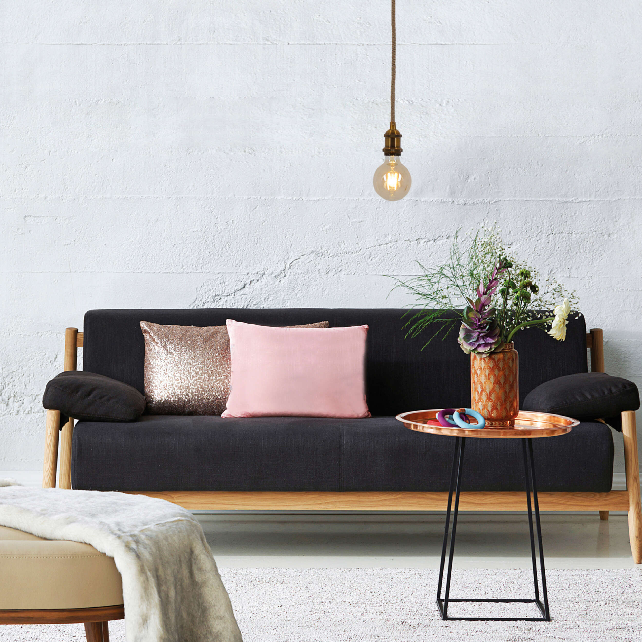 Ein Sofa mit Kissen, ein Couchtisch mit Vase und eine hängende Glühbirne.