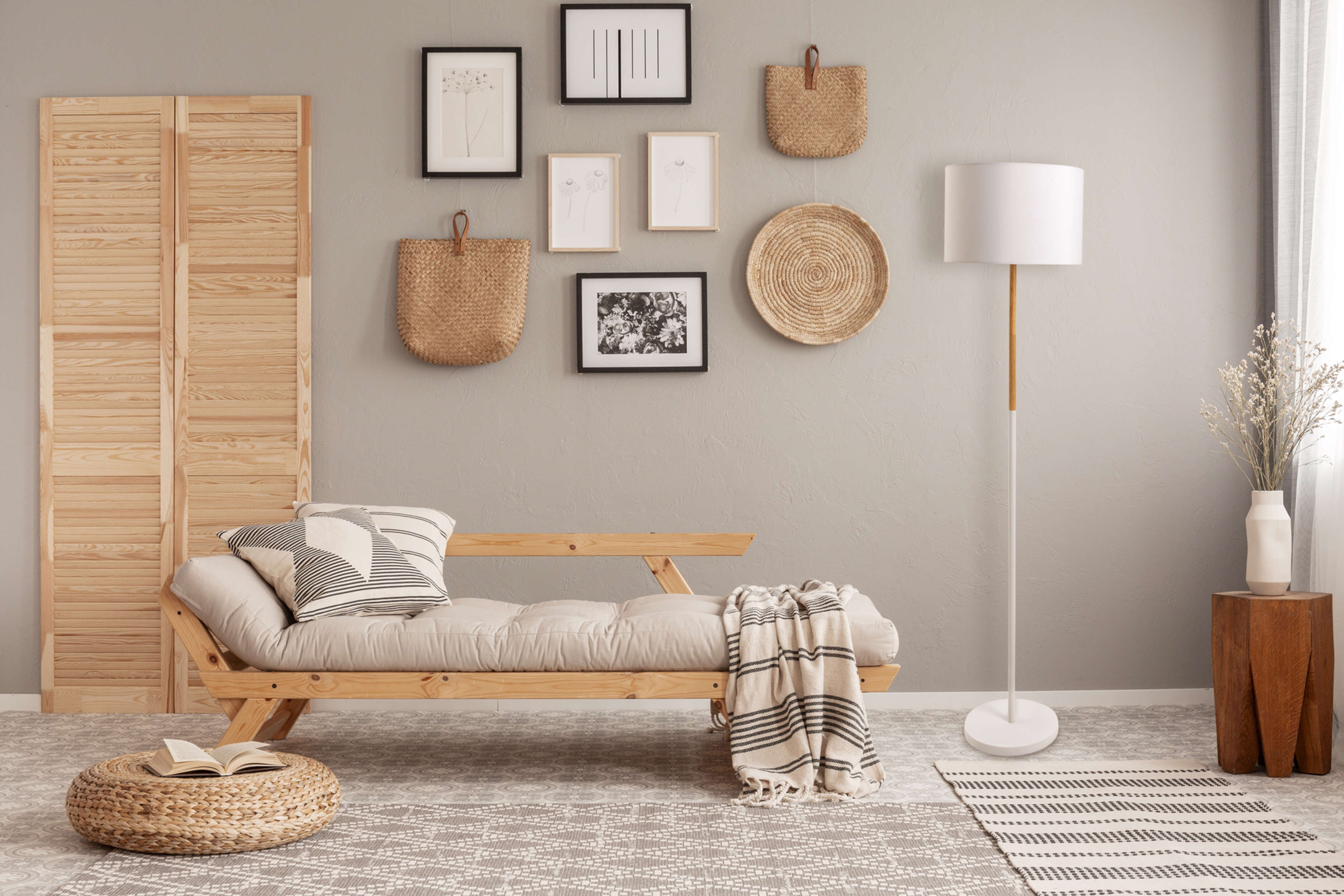 Aménagement de salon confortable avec futon, lampadaire, objets décoratifs et tapis.