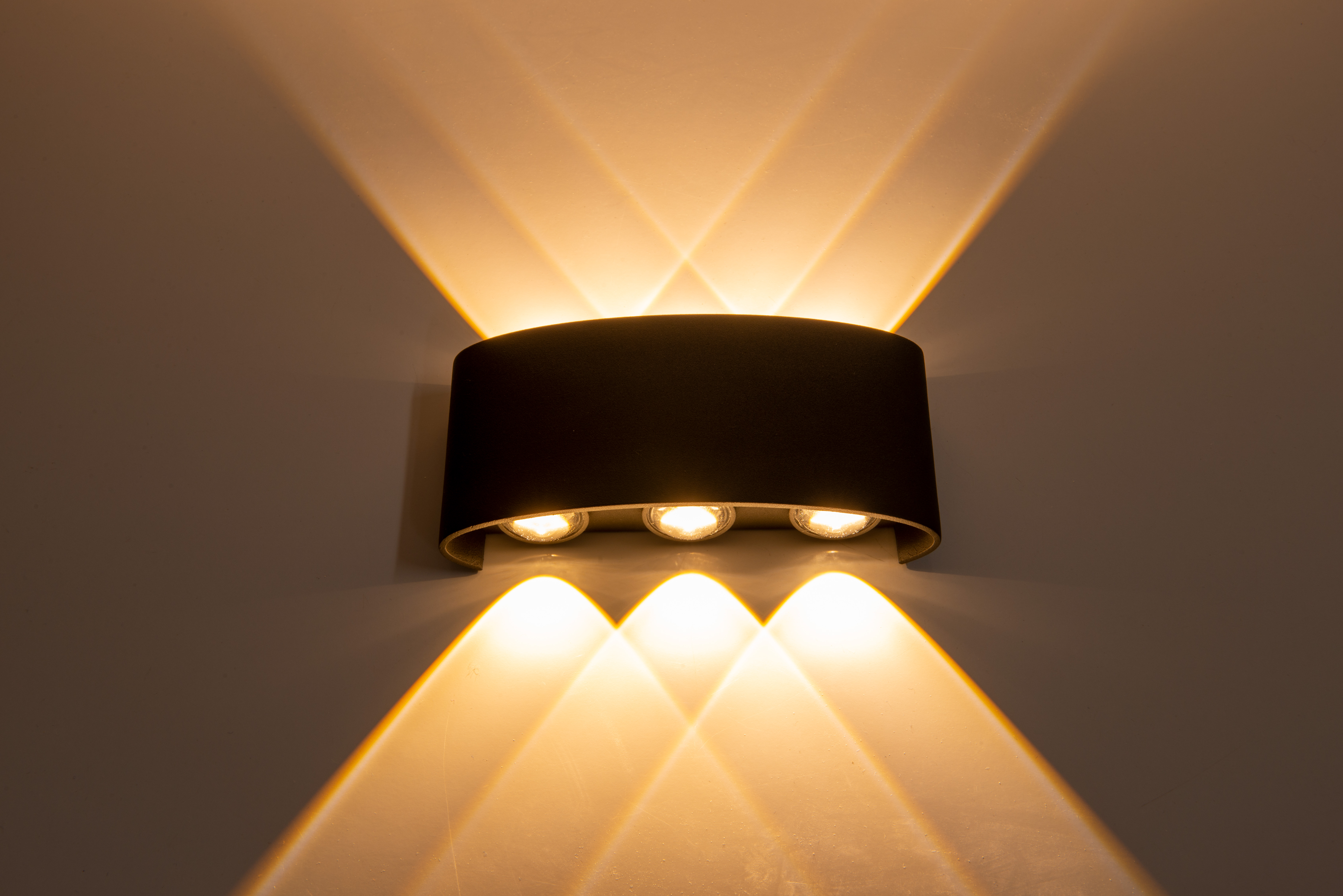 Eine schwarze Wandleuchte mit drei Glühbirnen, die Licht nach oben und unten wirft.